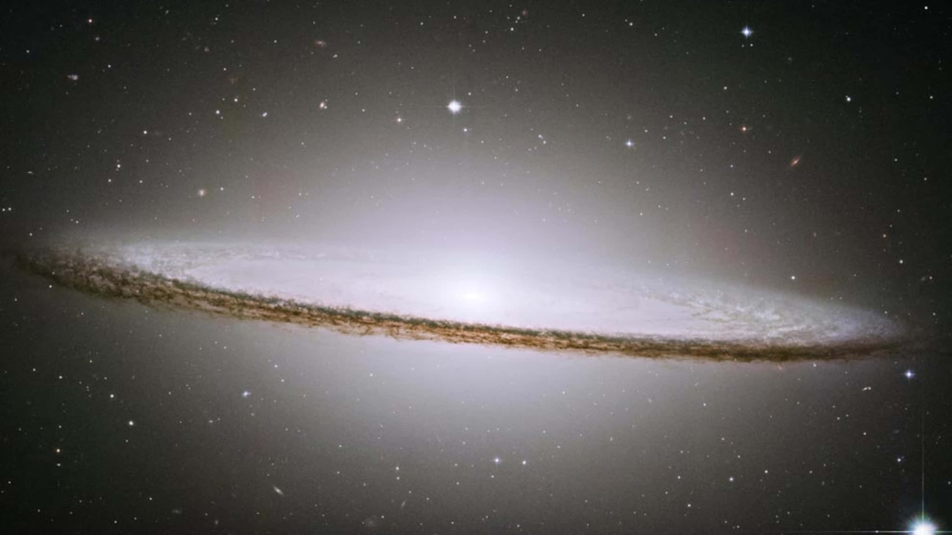Elliptical Galaxy 桌布 壁紙 — 一個令人驚嘆的側向螺旋星系，在星空中閃耀著明亮的白色和金色塵埃帶。