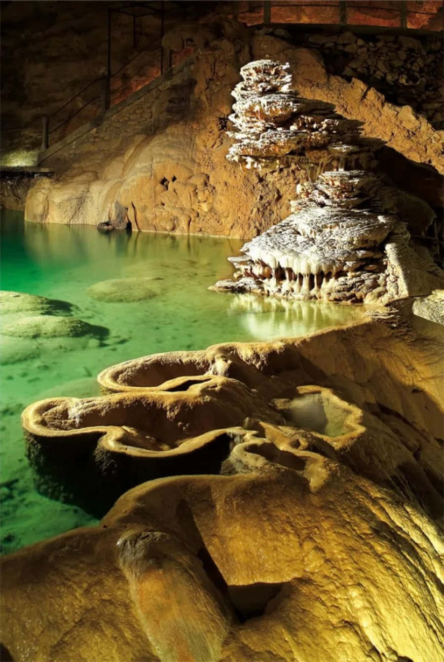 Cave 桌布 壁紙 — 一個令人驚嘆的地下洞穴，擁有溫暖的金色岩層和一個充滿活力的綠色水池，反射出洞穴複雜的紋理。
