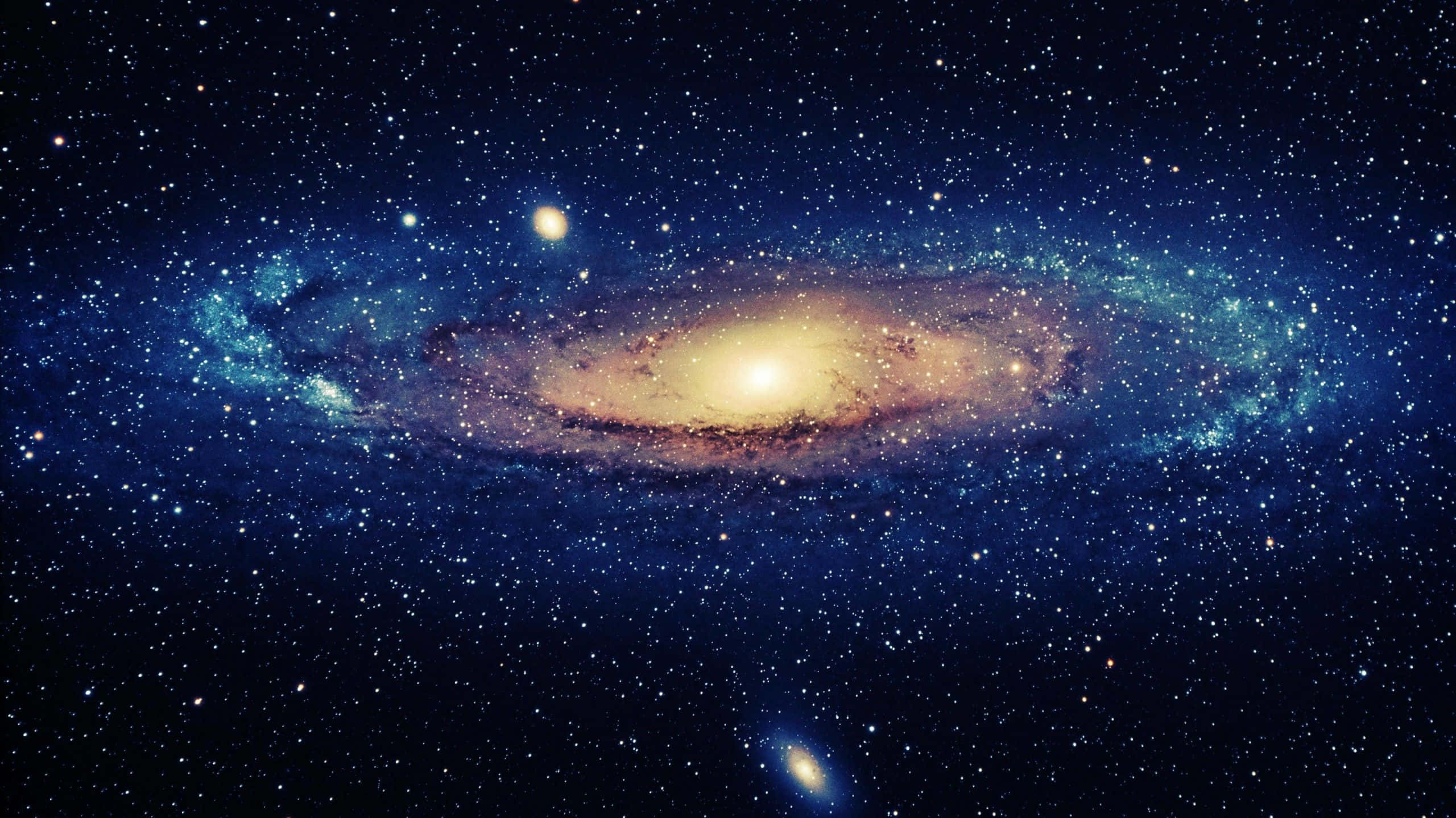 Black Galaxy 桌布 壁紙 — 一個令人驚嘆的螺旋星系，在星空中閃耀著金色核心和藍色星雲。