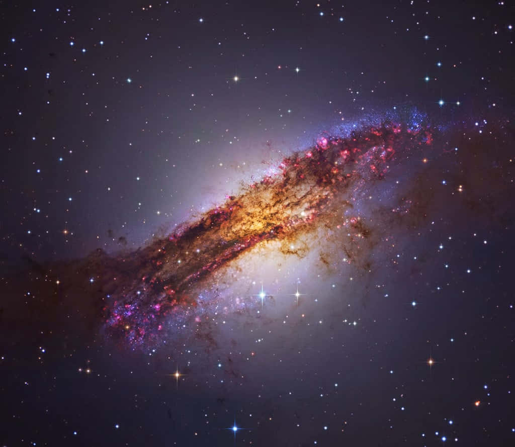 Elliptical Galaxy 桌布 壁紙 — 一個令人驚嘆的螺旋星系在星空中散發出充滿活力的粉紅色、紫色和金色色調。