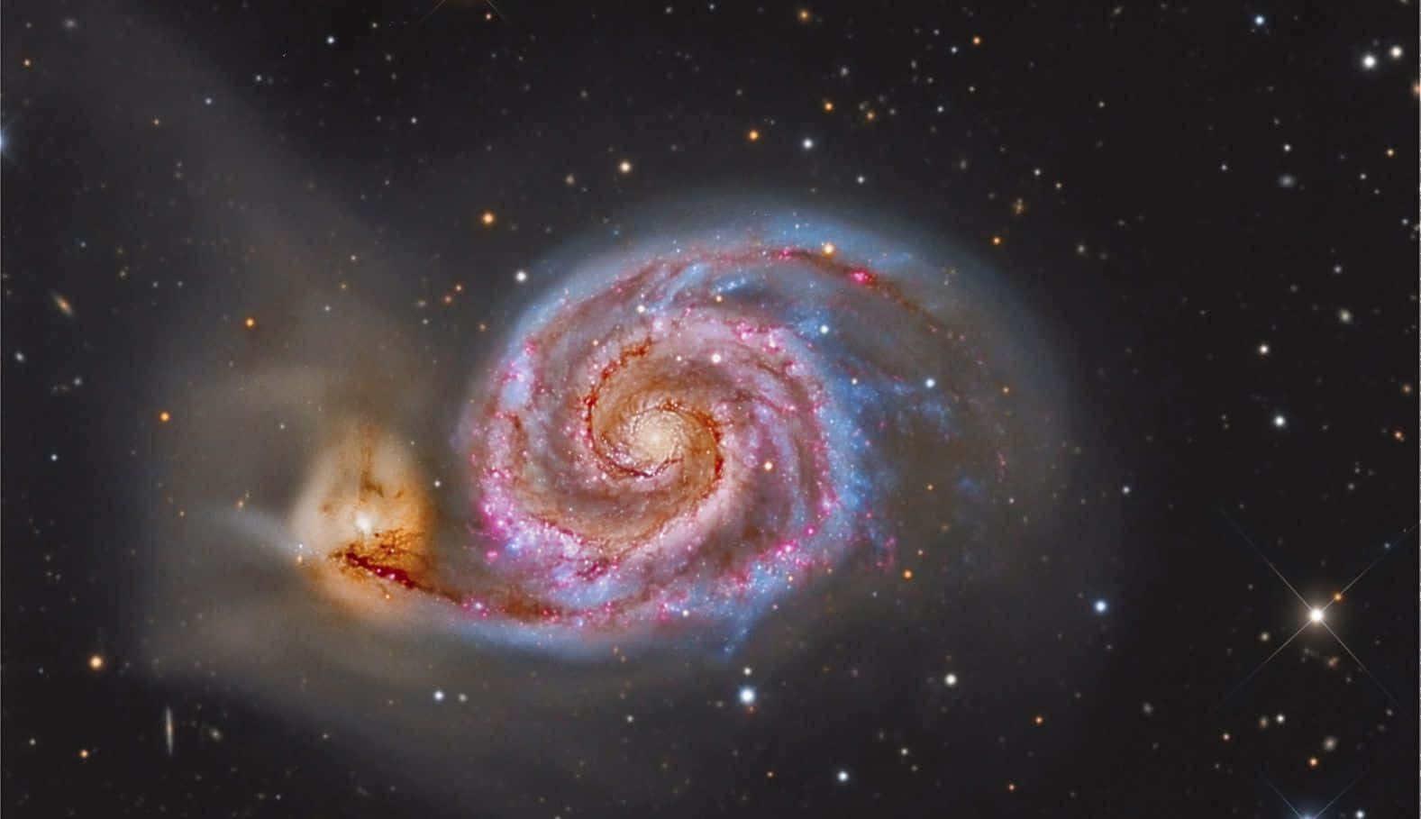 Whirlpool Galaxy 桌布 壁紙 — 一個令人驚嘆的螺旋星系在星空背景下旋轉，呈現粉紅色、藍色和橙色色調。