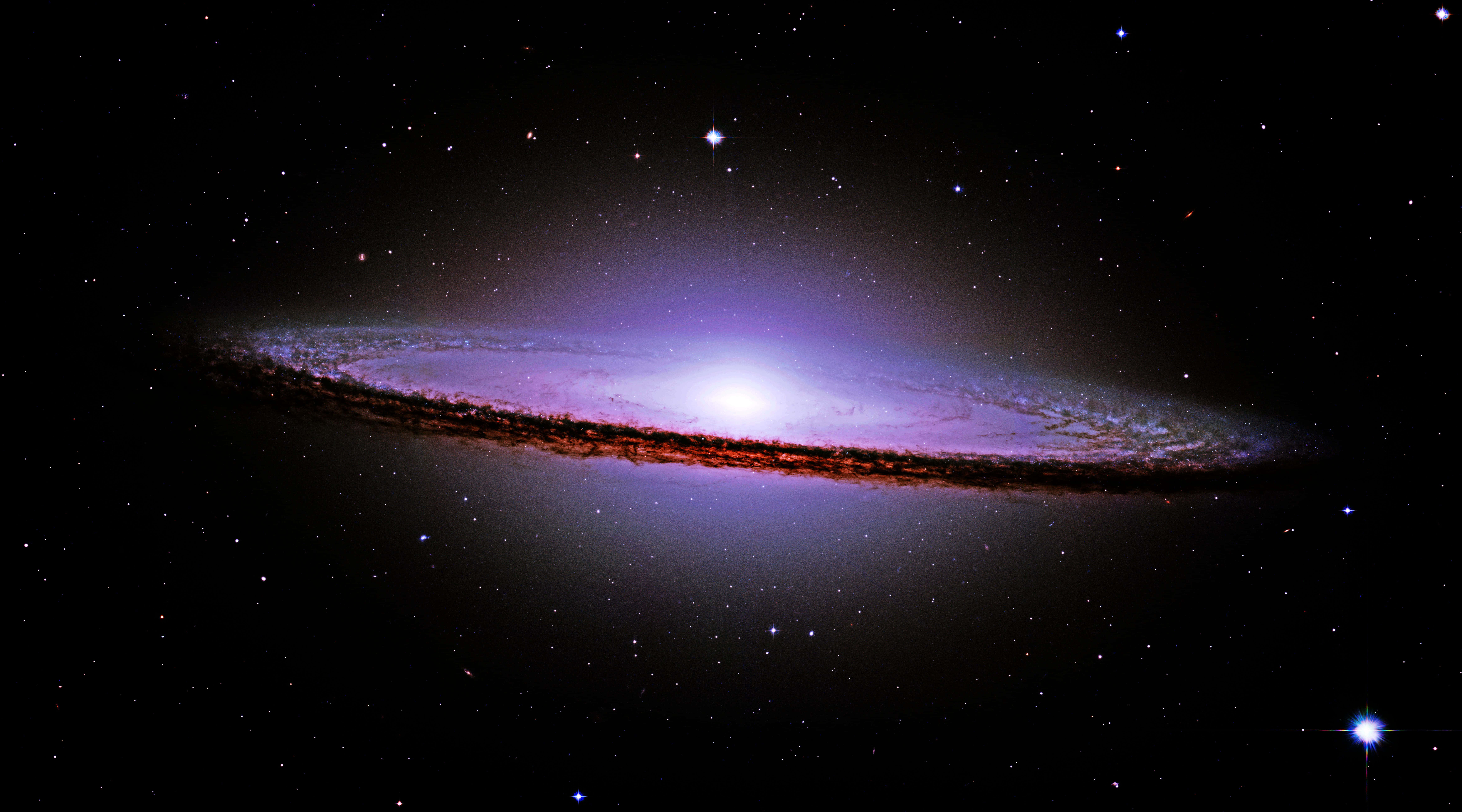 Sombrero Galaxy 桌布 壁紙 — 一個令人驚嘆的螺旋星系在深空的星場中散發出紫色和紅色的光芒。