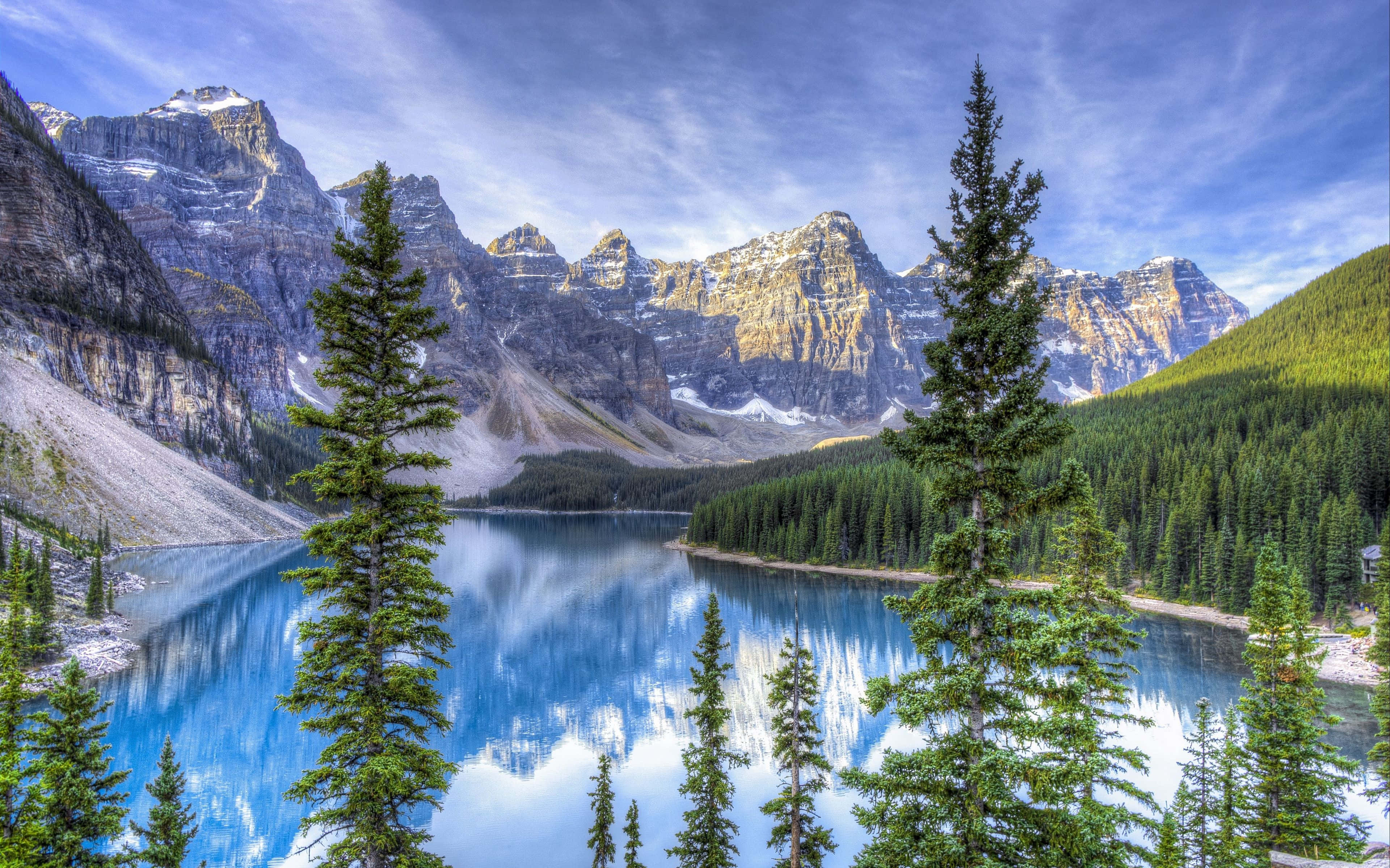 4K Hdr 桌布 壁紙 — 一個令人驚嘆的高山湖泊，在蔚藍天空和縷縷白雲下，映照著白雪覆蓋的山峰和松樹。