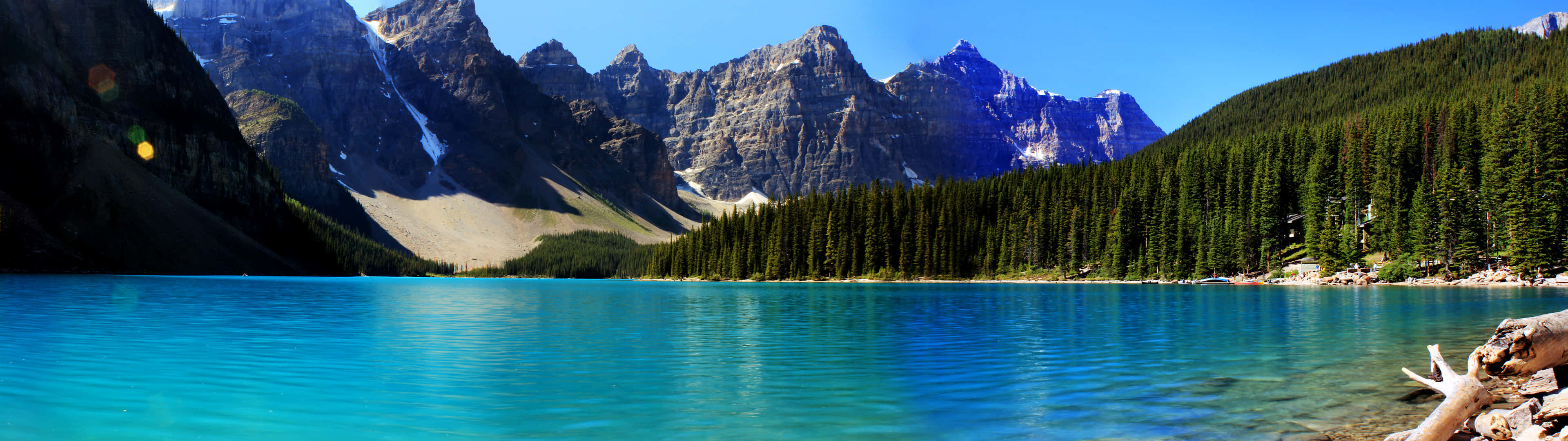Canada 桌布 壁紙 — 一個令人驚嘆的高山湖泊，碧綠色的湖水映照著在晴朗藍天下鋸齒狀、覆蓋著白雪的山峰。
