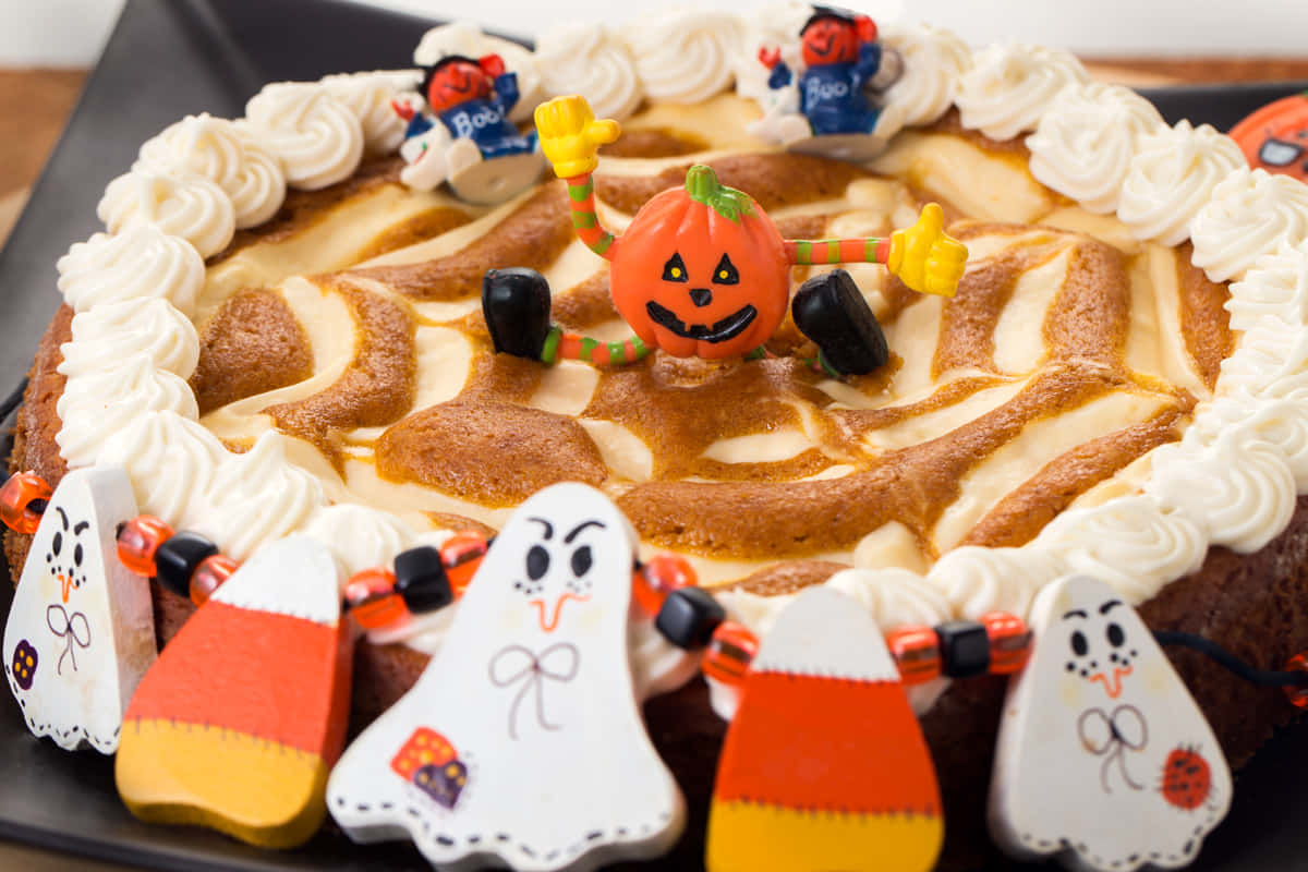 Halloween Cake 桌布 壁紙 — 一個以萬聖節為主題的蛋糕，裝飾有忌廉蜘蛛網、微笑的傑克南瓜燈裝飾和糖果玉米鬼魂曲奇。