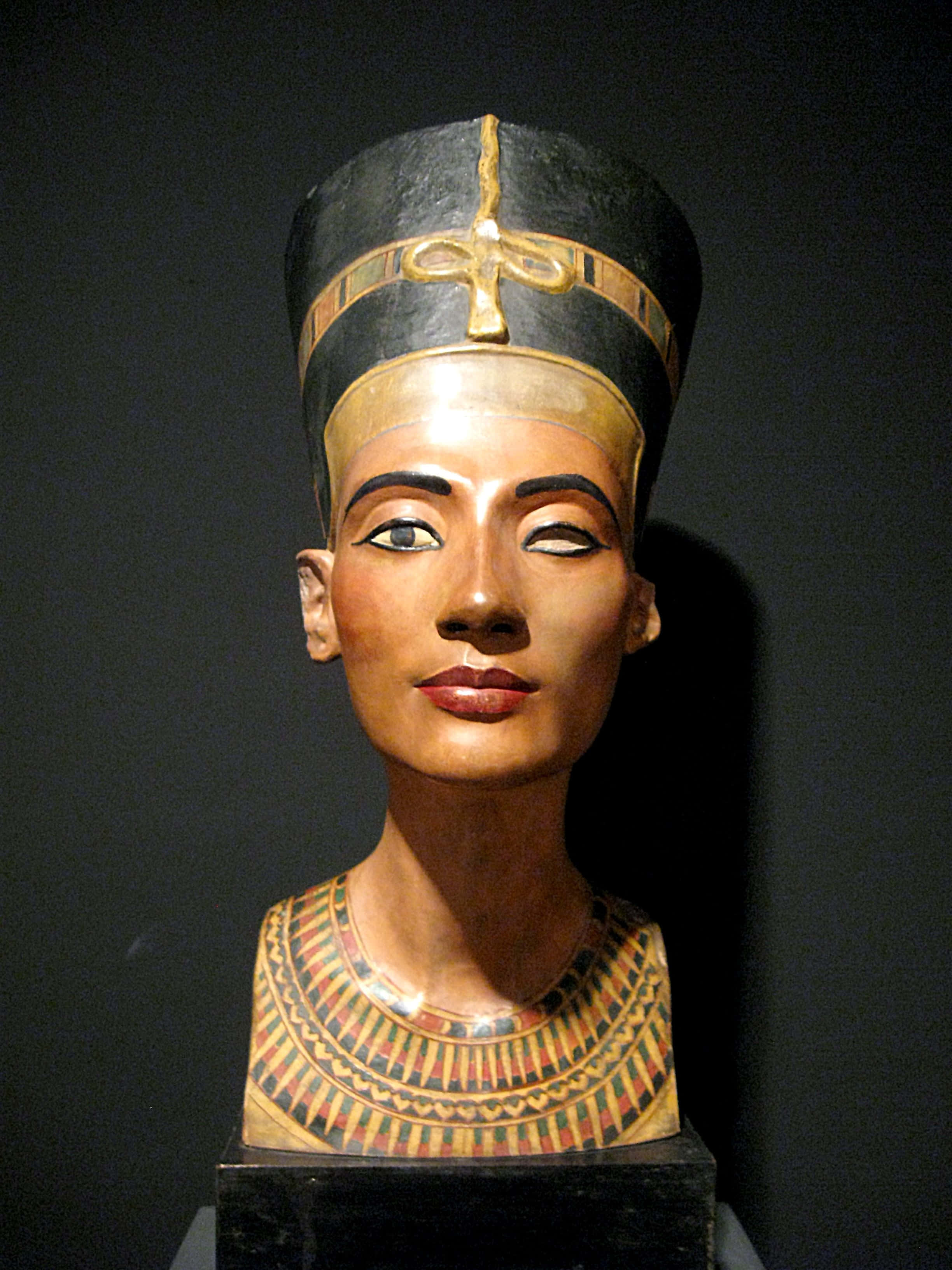 Cleopatra 桌布 壁紙 — 一個保存得驚人地完好的古埃及娜芙蒂蒂王后半身像，戴著金色頭飾和精緻的項圈，背景深色。