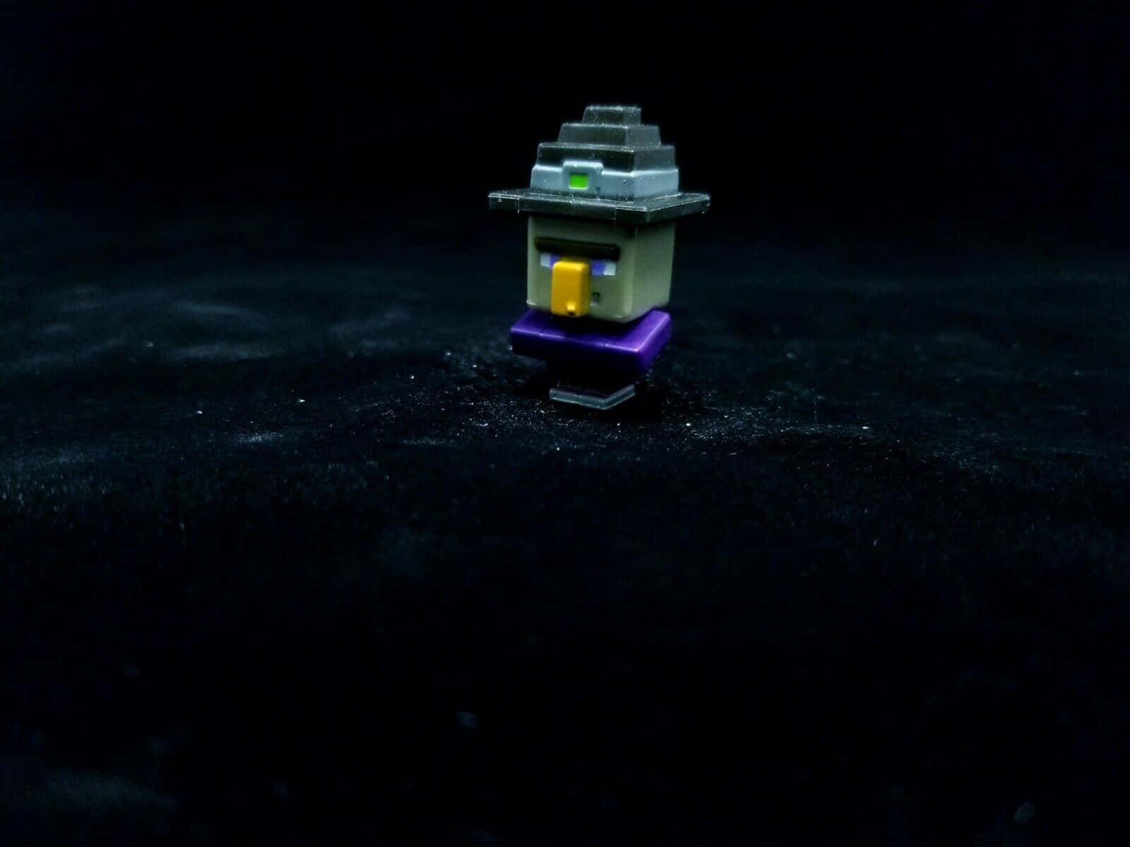Minecraft Witch 桌布 壁紙 — 一個像素化的Minecraft女巫公仔獨自站在黑暗紋理表面上，在戲劇性的聚光燈下。