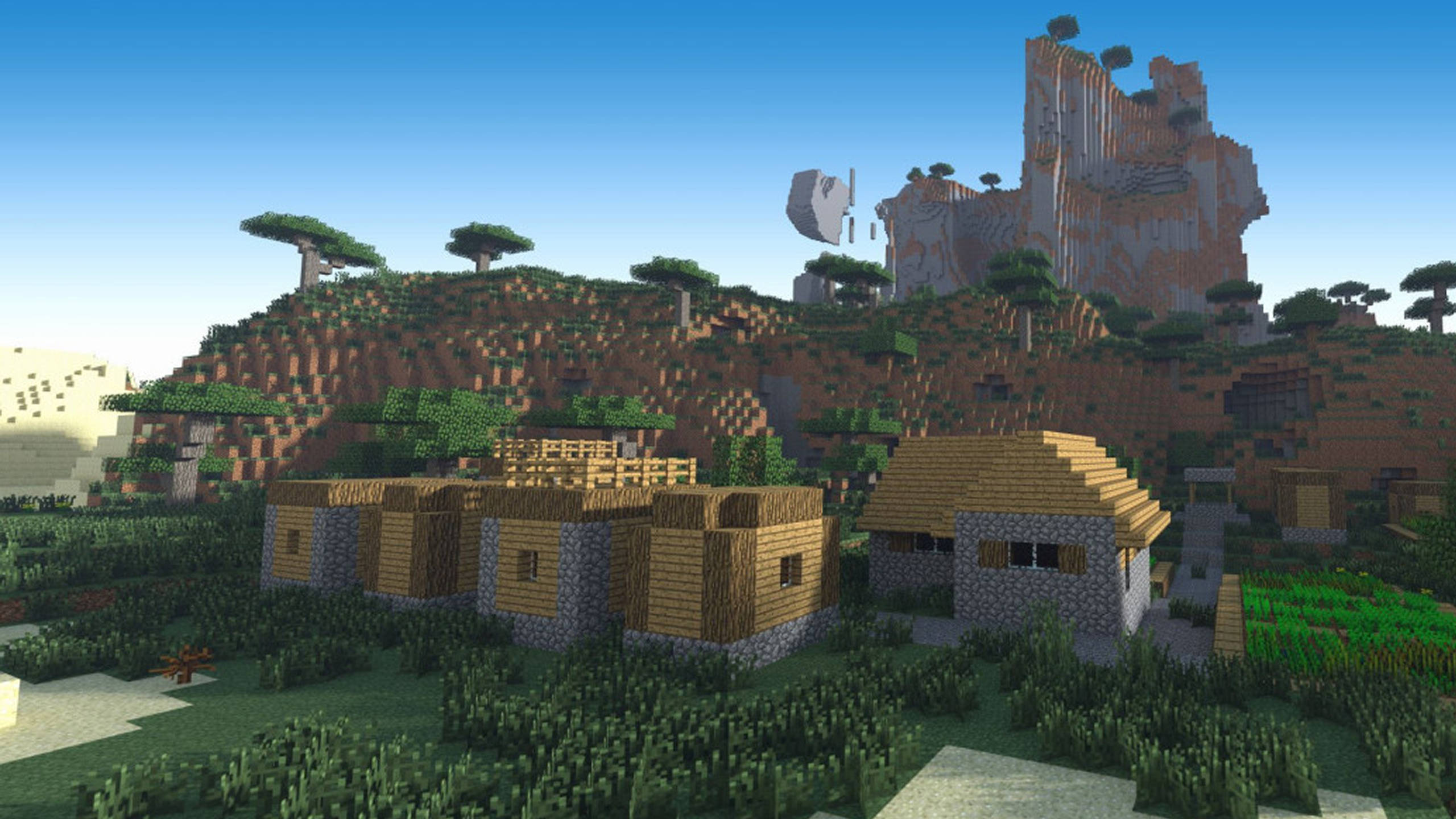 Minecraft HD 桌布 壁紙 — 一個像素化的Minecraft村莊，坐落在長滿草的谷地中，有木屋、石頭地基和背後高聳的懸崖。