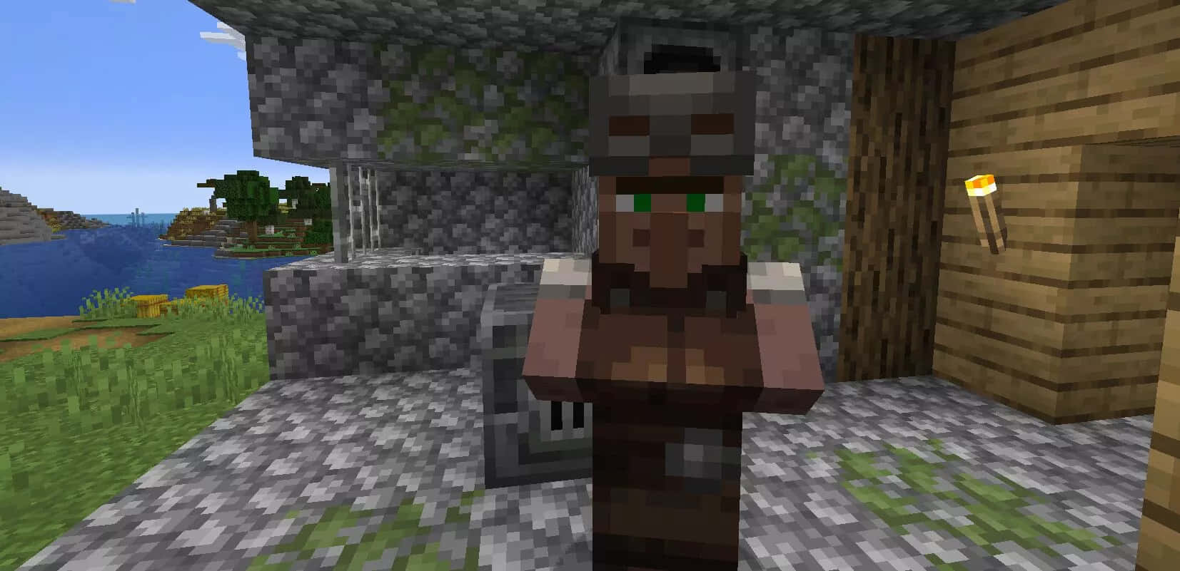 Minecraft Villager 桌布 壁紙 — 一個像素化的Minecraft村民站在一間石頭和木頭建造的房屋前，房屋點著火炬，俯瞰著草地景觀和藍天白雲下的海洋。