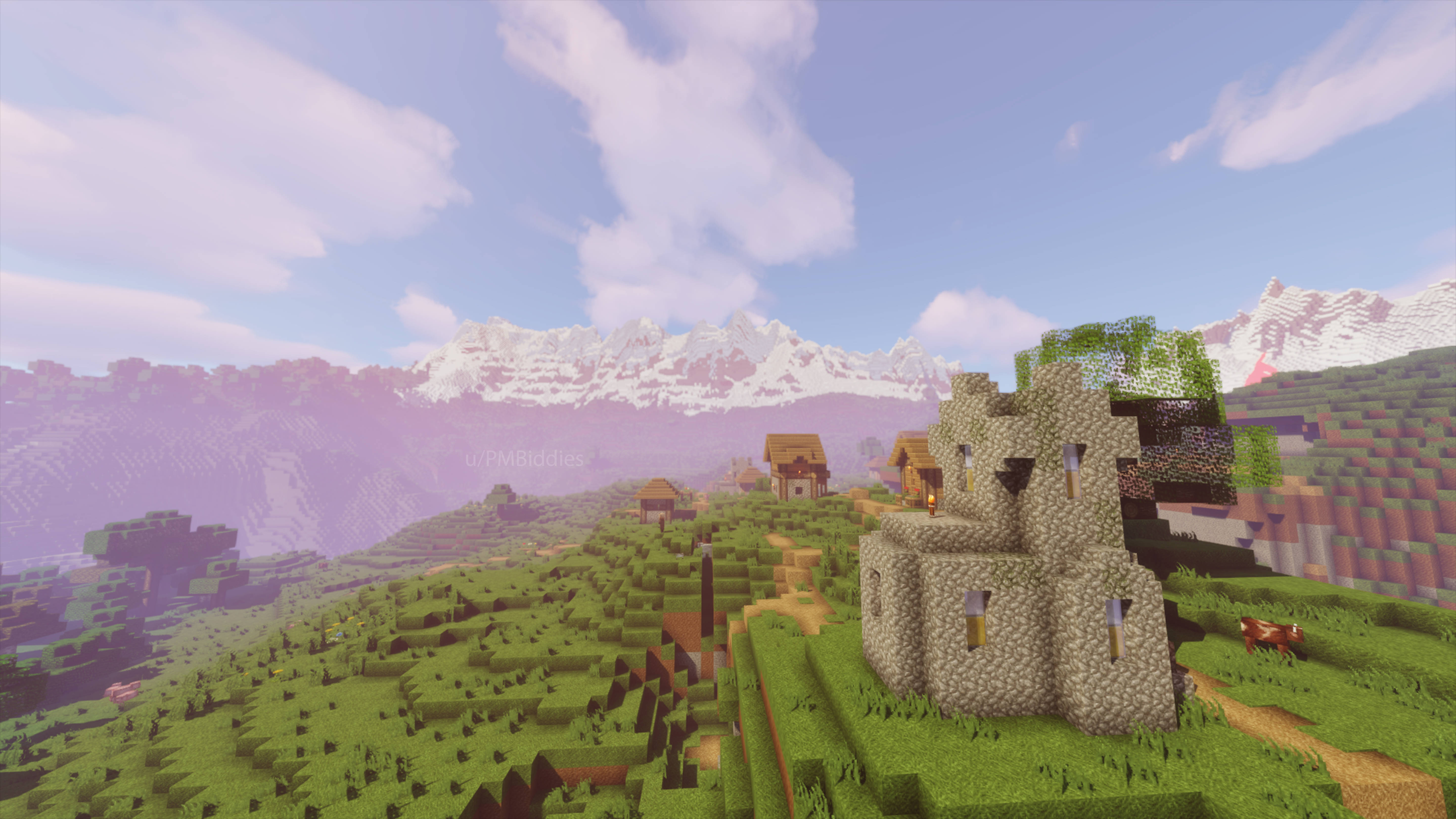 森林 桌布 壁紙 — 一個像素化的Minecraft村莊，石頭城堡和木屋坐落在綠色山丘上，藍天白雲下遠方有雪山。
