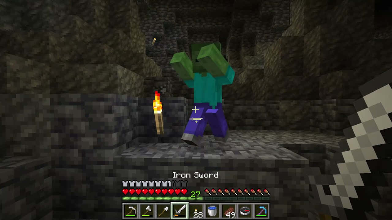 Minecraft Zombie 桌布 壁紙 — 一個像素化的喪屍喺Minecraft洞穴入面揸住火炬，而玩家就用第一人稱視角揮動鐵劍。