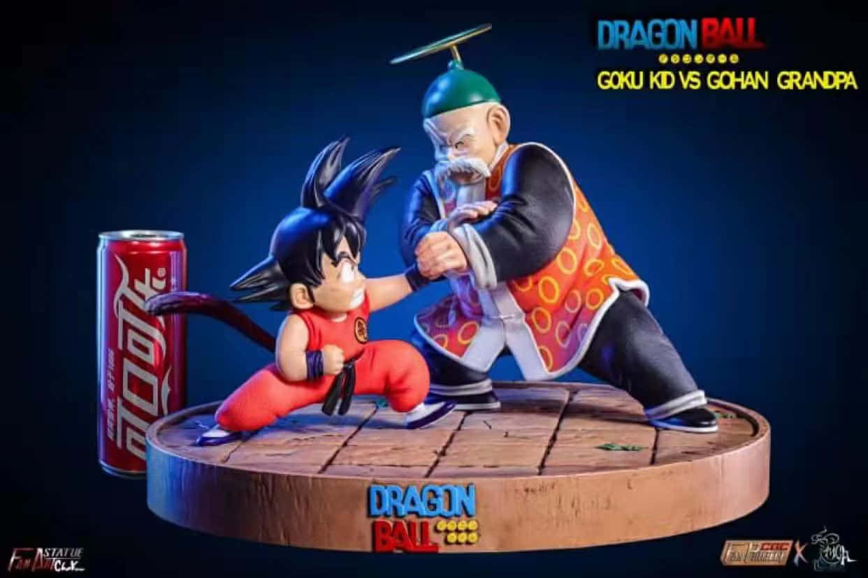 Grandpa Gohan 桌布 壁紙 — 一個充滿動感的龍珠雕像，展示身穿紅色衣服的年輕悟空在木製平台上與白髮的爺爺悟飯戰鬥，旁邊有一罐可口可樂。