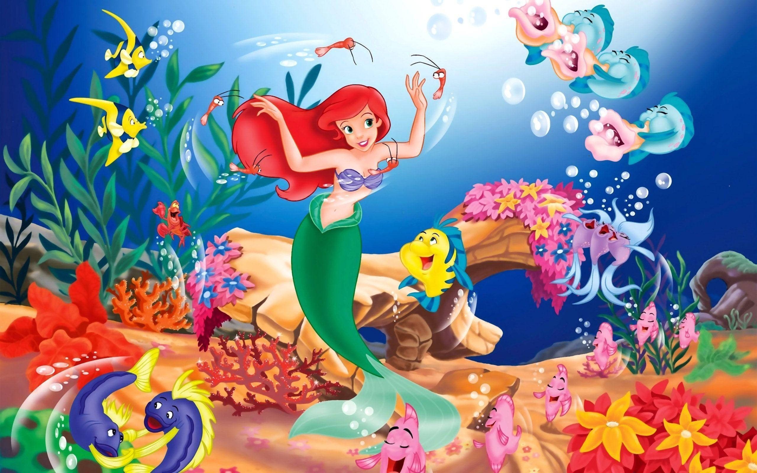 Disney Princess 桌布 壁紙 — 一個充滿活力的卡通美人魚，紅髮綠尾，在陽光明媚的水下王國中，在色彩繽紛的珊瑚和快樂的海洋生物之間歡快地跳舞。