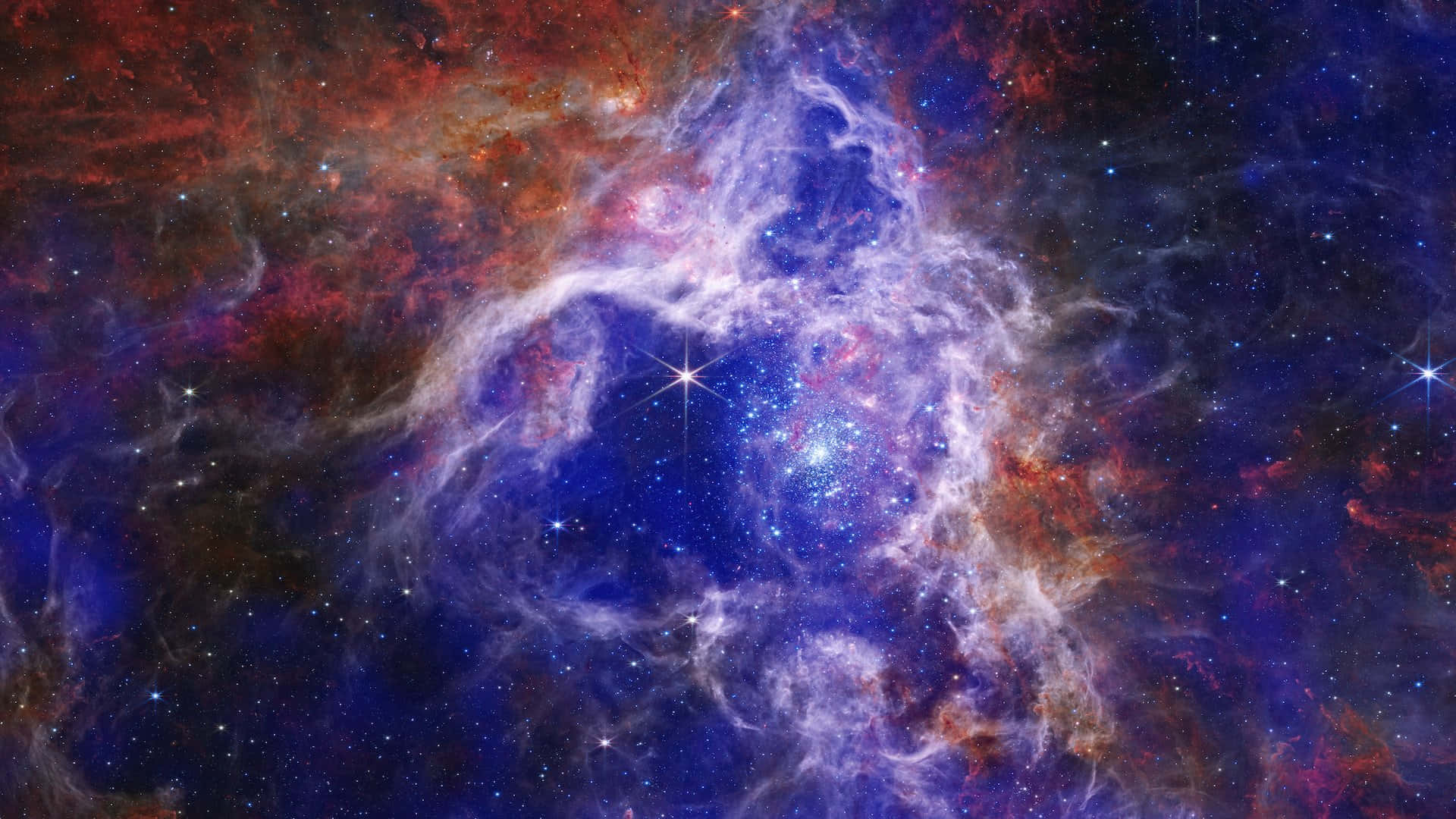 Spectacular 桌布 壁紙 — 一個充滿活力的宇宙星雲，在佈滿星辰的虛空中，旋轉著電光藍和火熱紅。