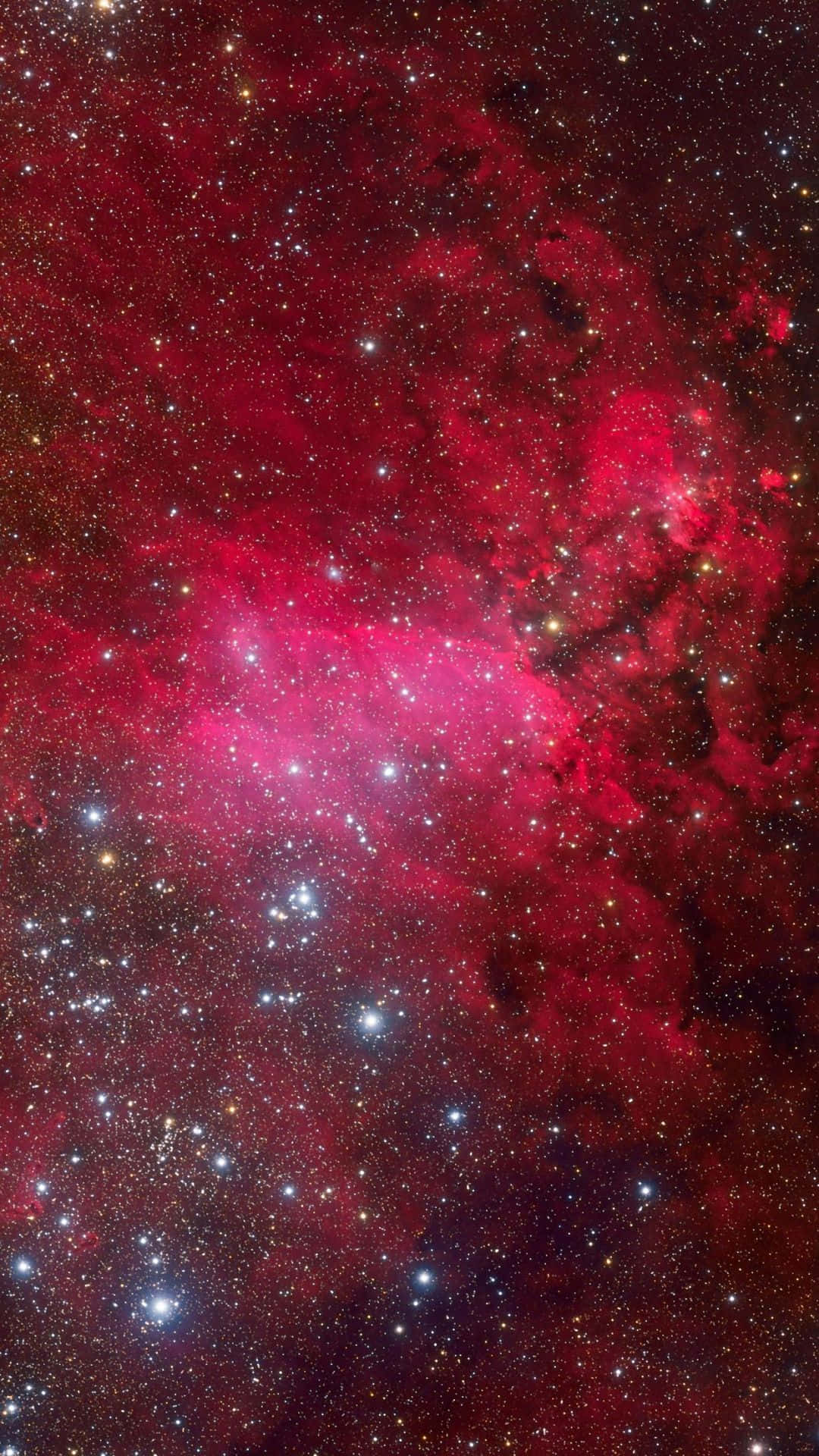 紅色 iPhone 壁紙 桌布 壁紙 — 一個充滿活力的宇宙星雲，在深紅色和粉紅色中發光，黑暗虛空中散佈著明亮的星星。