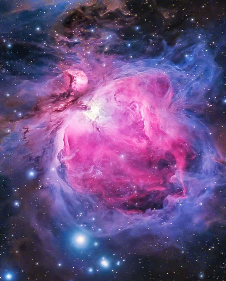 Interstellar Cloud 桌布 壁紙 — 一個充滿活力的宇宙星雲，在黑暗的星場中，由明亮的星星照亮，旋轉著粉紅色、紫色和藍色的氣體。