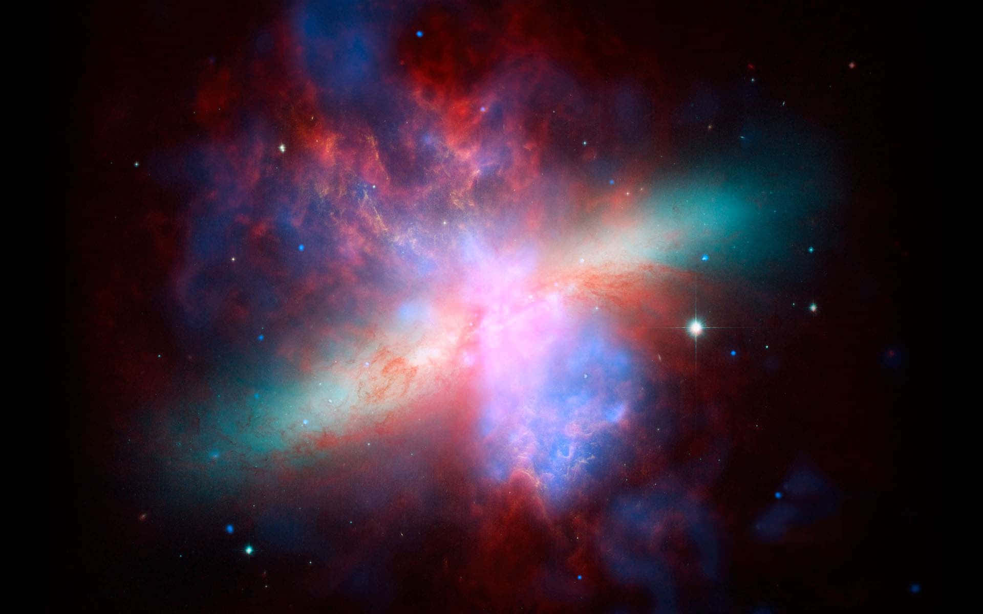 Supernova Explosion 桌布 壁紙 — 一個充滿活力的宇宙星雲在佈滿星星的黑色虛空中爆發紅色、藍色和粉紅色的氣體。