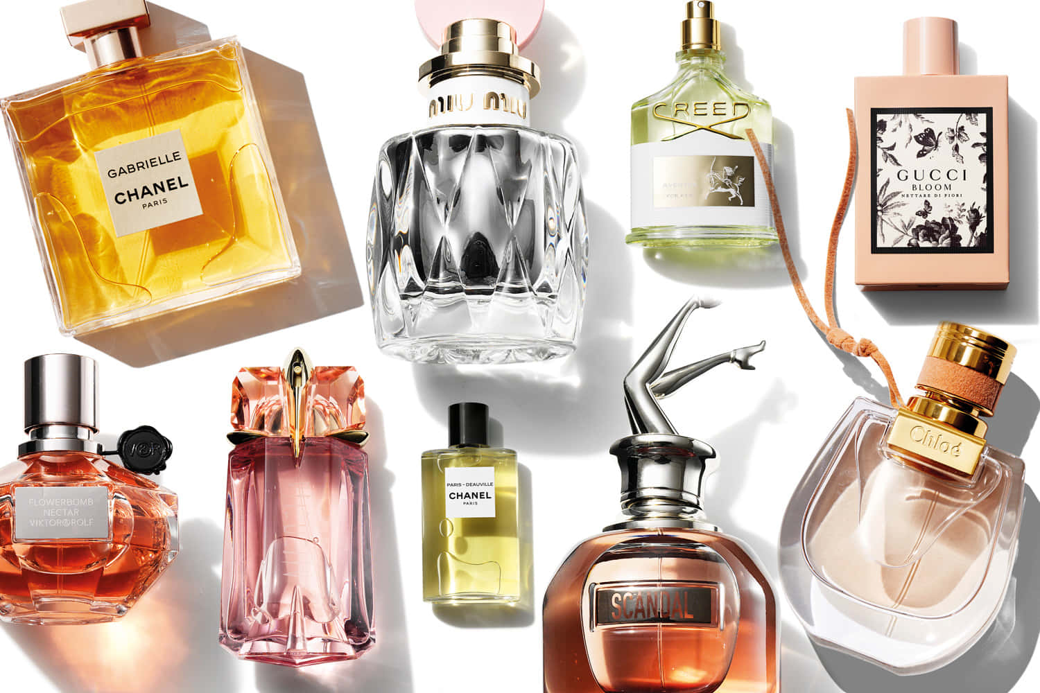 Fragrance 桌布 壁紙 — 一個充滿活力的平鋪佈局，展示 Chanel、Gucci 和 Creed 的奢華香水瓶，在明亮的白色表面上投射出銳利的陰影。