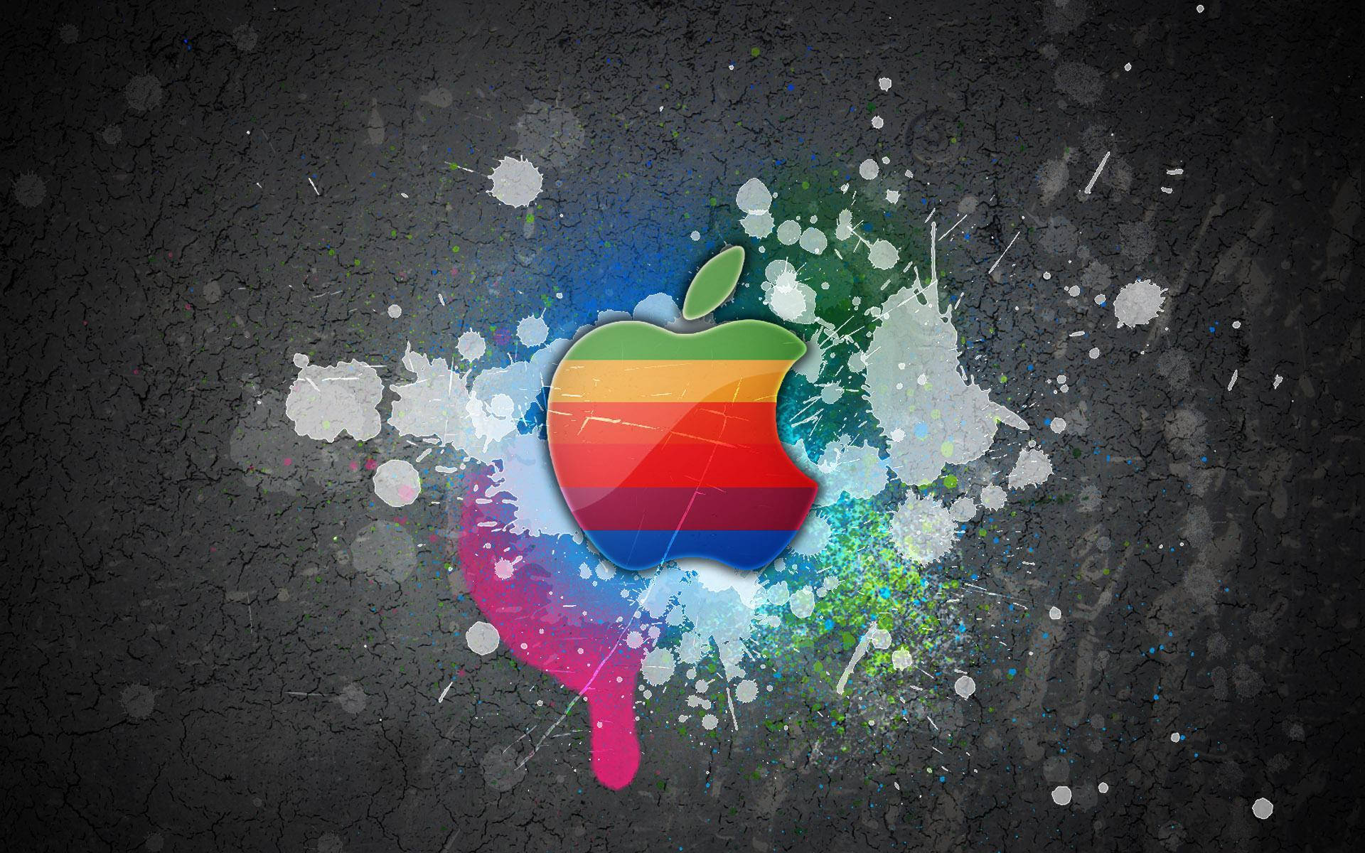 蘋果 桌布 壁紙 — 一個充滿活力的彩虹Apple標誌，在裂開的深色混凝土背景上爆發出色彩繽紛的油漆飛濺。