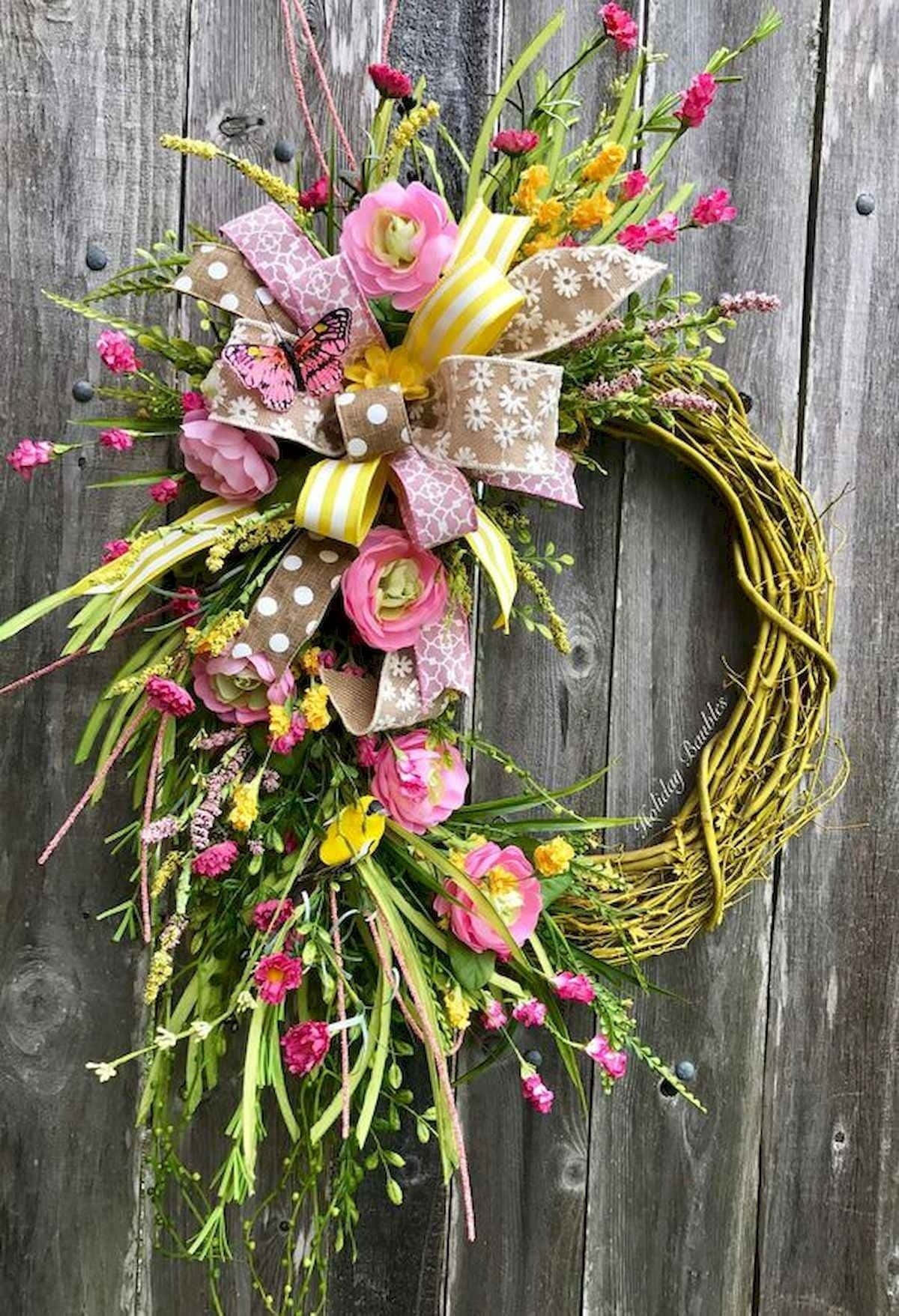 Spring Wreaths 桌布 壁紙 — 一個充滿活力的春天花環，帶有粉紅色和黃色的花朵、綠葉和圖案蝴蝶結，掛在風化的木門上。