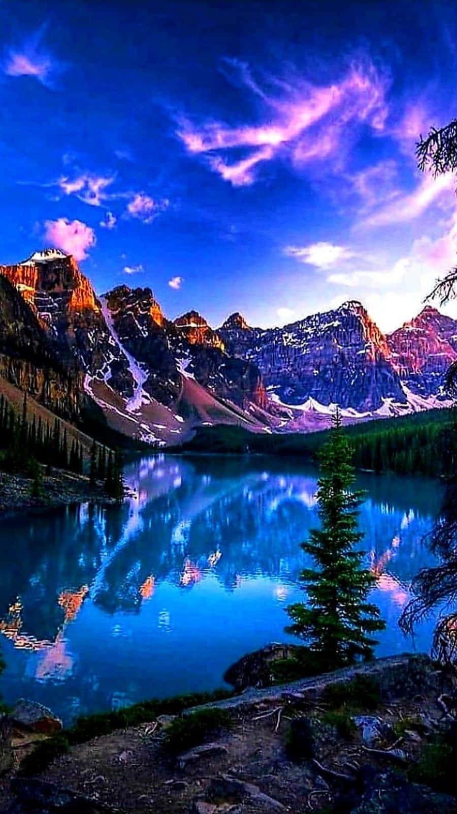 美景 桌布 壁紙 — 一個充滿活力的暮色山湖，映照著紫色和藍色的天空，伴隨著積雪的山峰和常綠樹木。