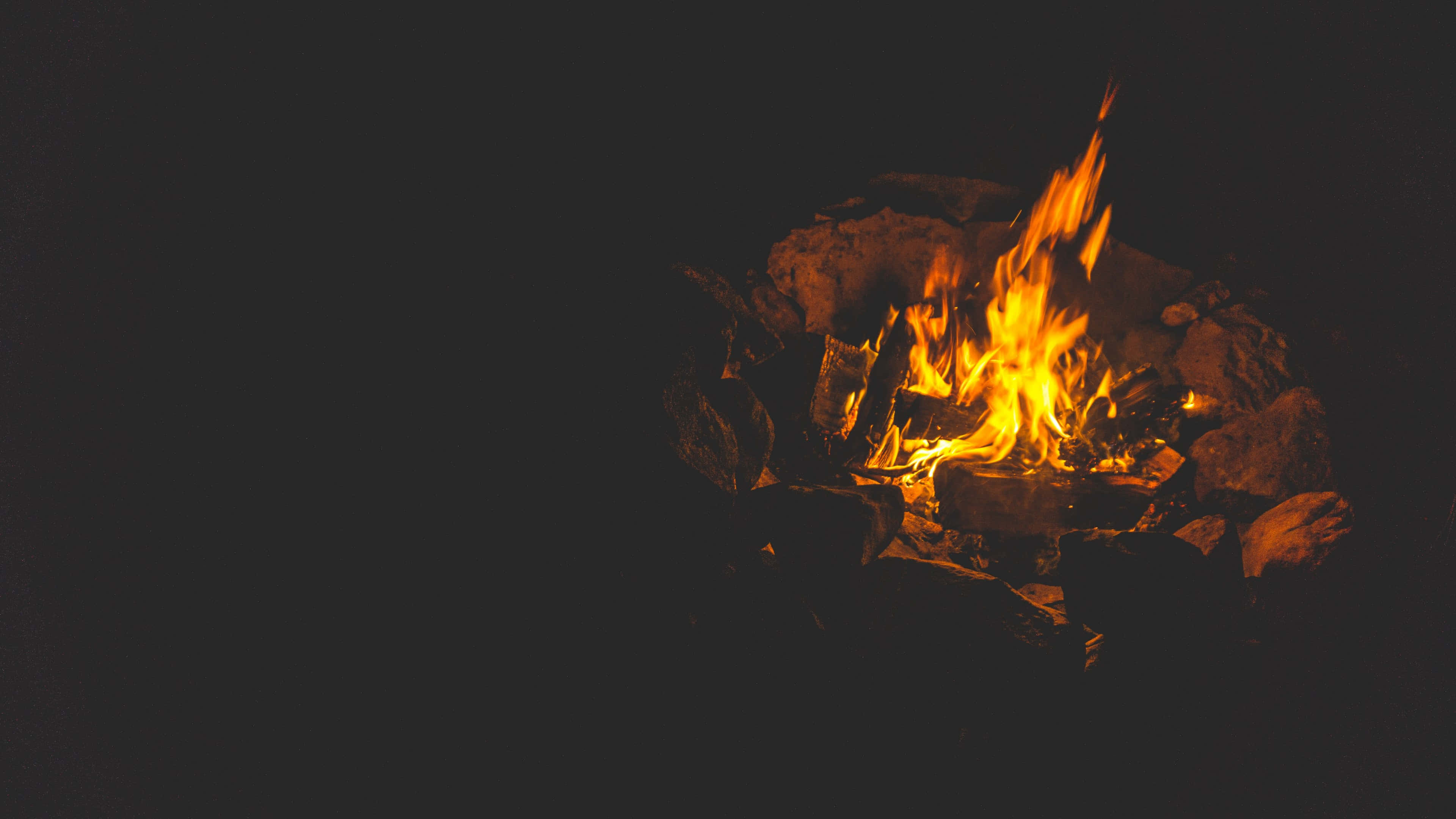 Fall Bonfire 桌布 壁紙 — 一個充滿活力的營火在漆黑的夜空中噼啪作響，橙色的火焰翩翩起舞。