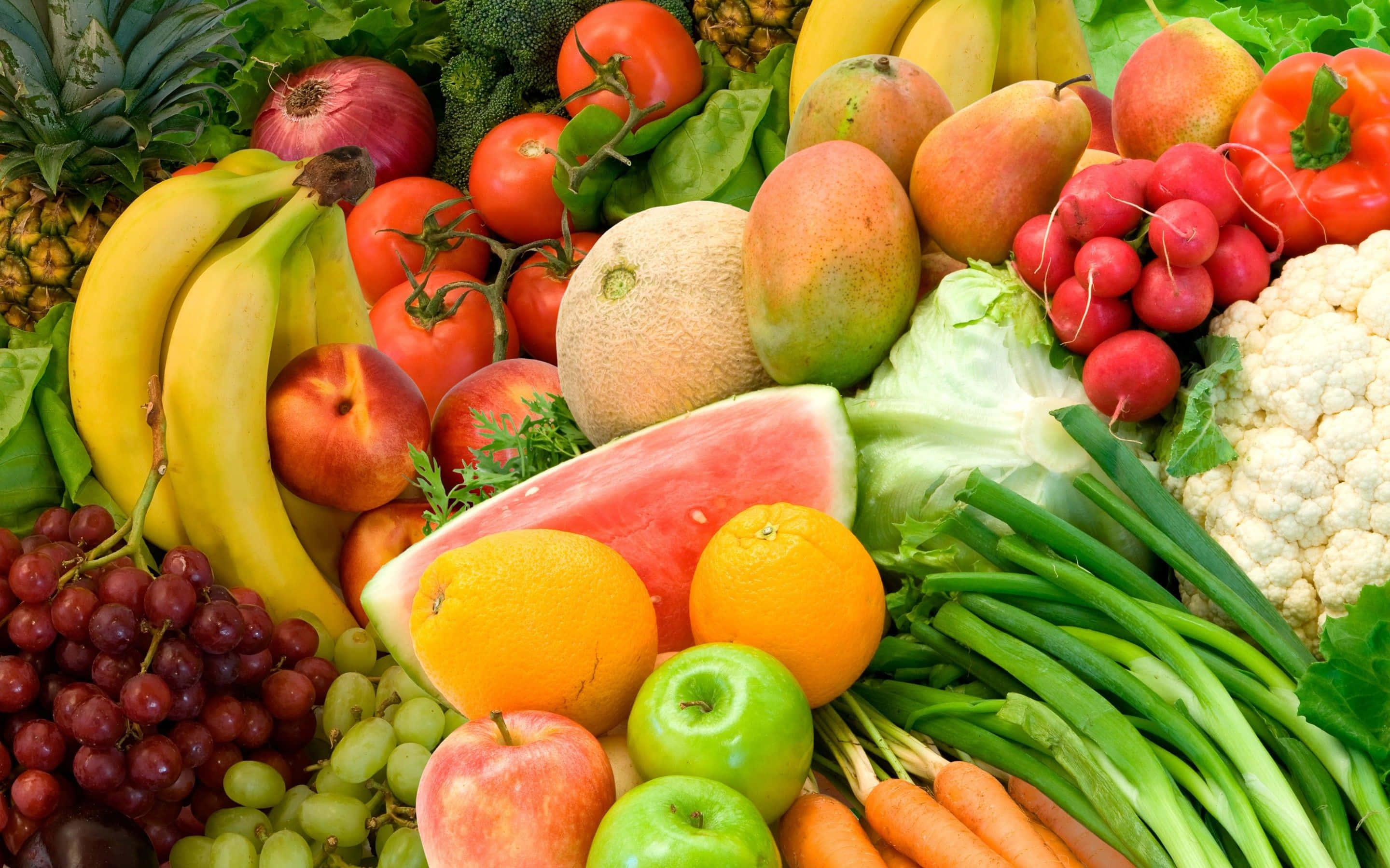 Vegetable 桌布 壁紙 — 一個充滿活力的特寫，展示了各種新鮮水果和蔬菜，包括香蕉、西瓜、葡萄和胡蘿蔔，排列成色彩繽紛且豐富的堆疊。
