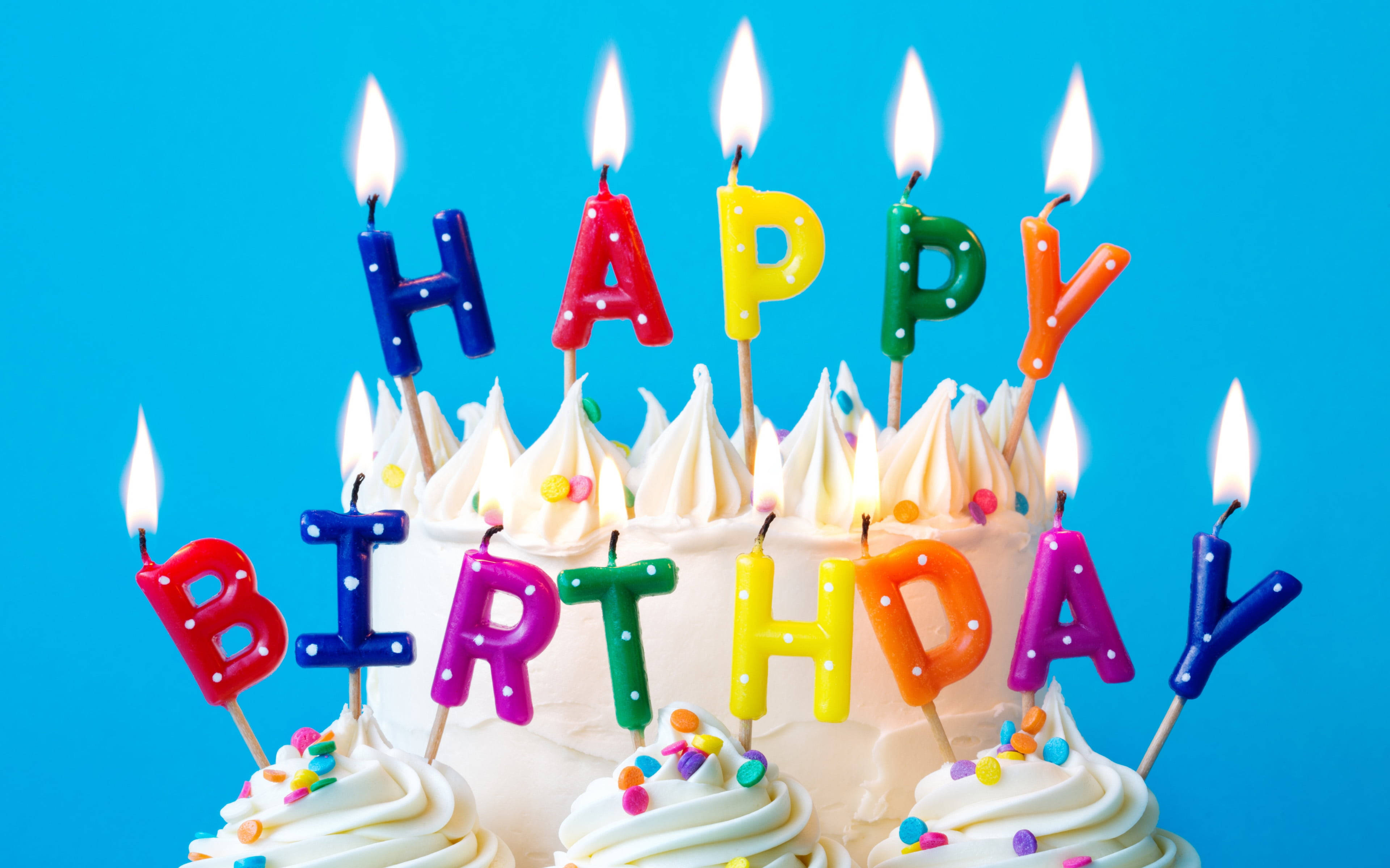 Birthday Cake 桌布 壁紙 — 一個充滿活力的生日蛋糕，上面裝飾著彩色字母蠟燭，在明亮的藍色背景上拼出「HAPPY BIRTHDAY」。
