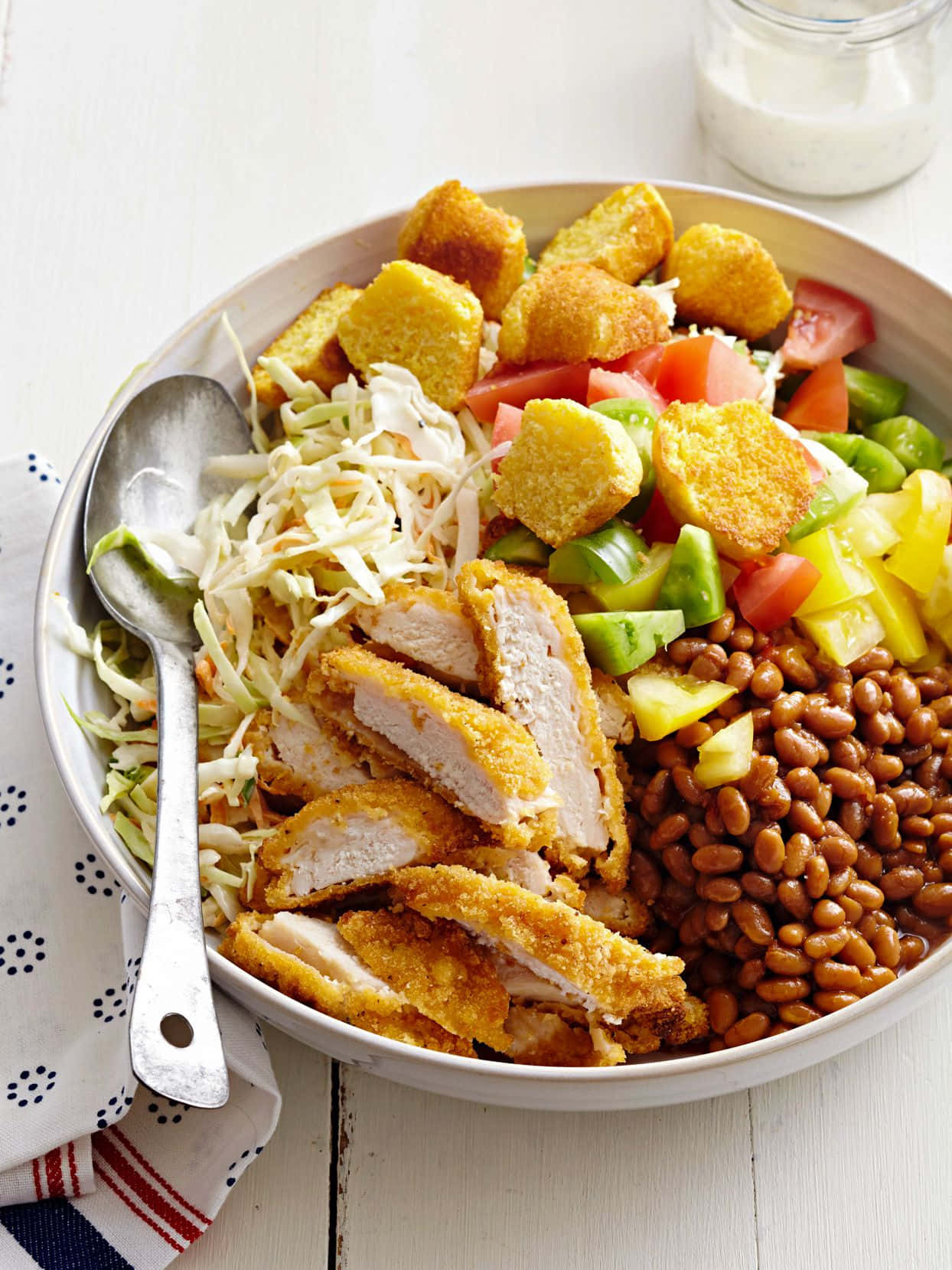 Beautiful Food 桌布 壁紙 — 一個充滿活力的碗，裡面有酥脆的炸雞片，混合了豆類、高麗菜沙拉、番茄和玉米麵包丁，放在白色木桌上。