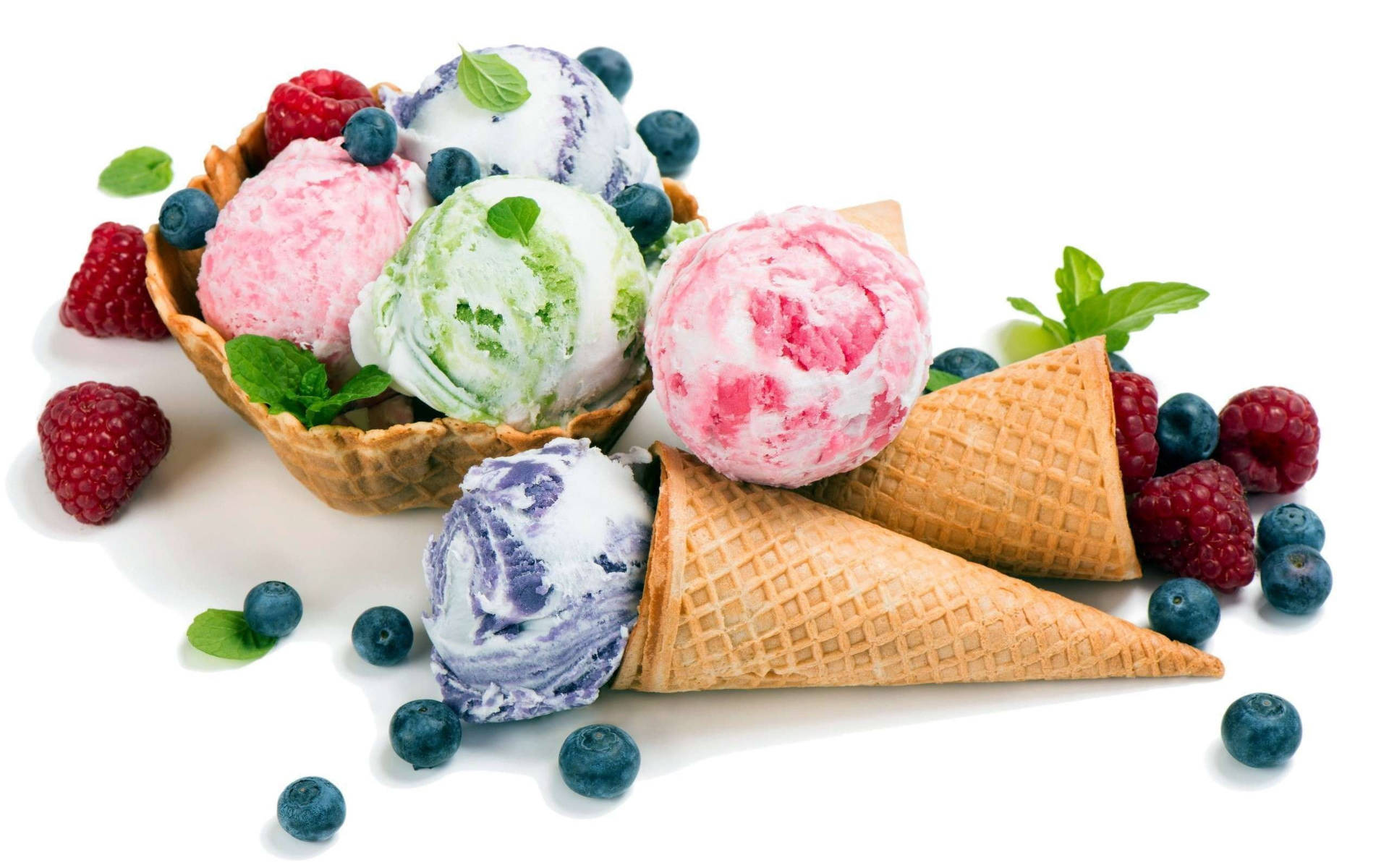 Berry 桌布 壁紙 — 一個充滿活力的碗和甜筒，上面有色彩繽紛的冰淇淋漩渦，配上新鮮的覆盆子、藍莓和薄荷葉，放在潔白的背景上。
