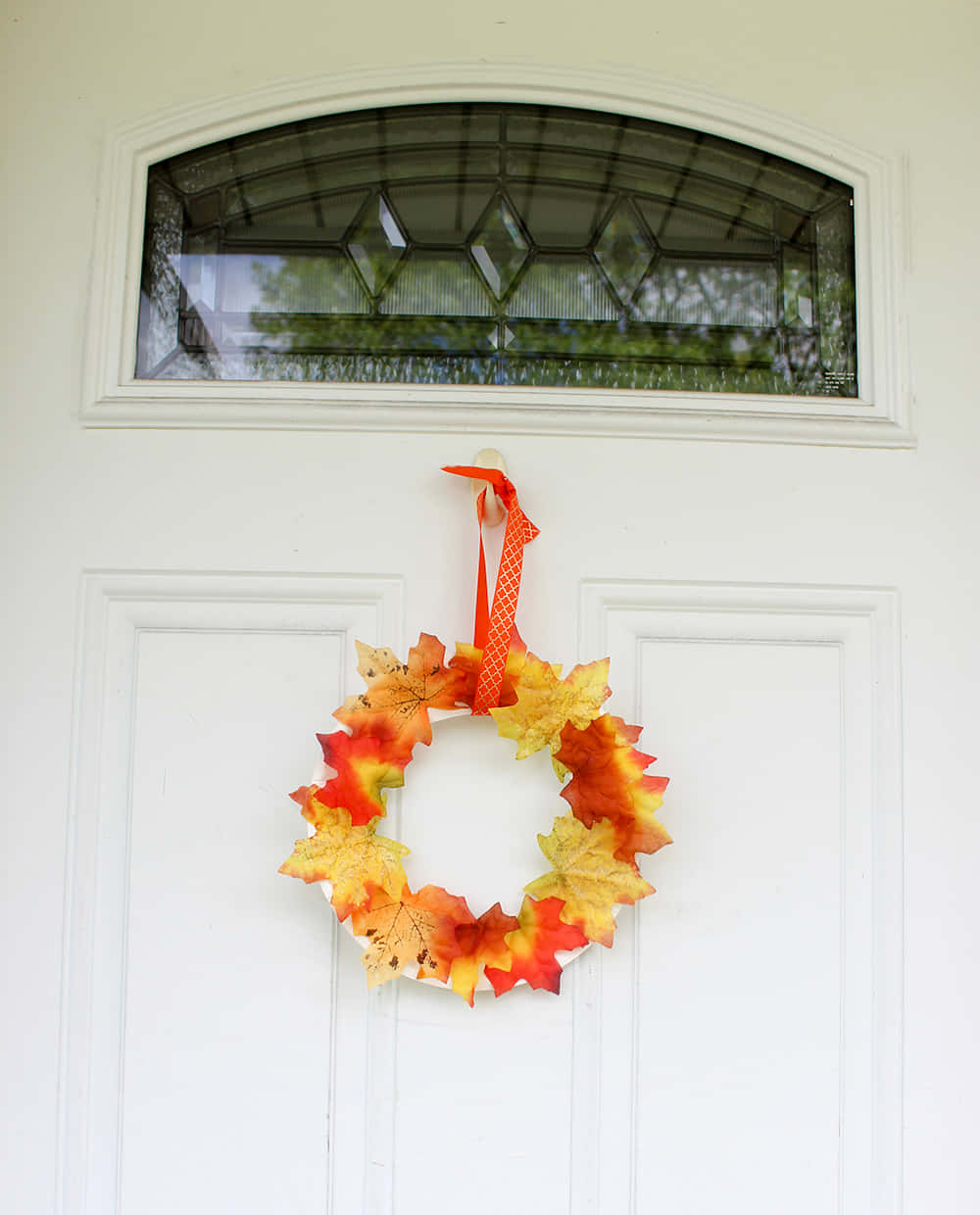 Fall Wreath 桌布 壁紙 — 一個充滿活力的秋葉花環掛在白色前門上，下方是彩色玻璃窗。