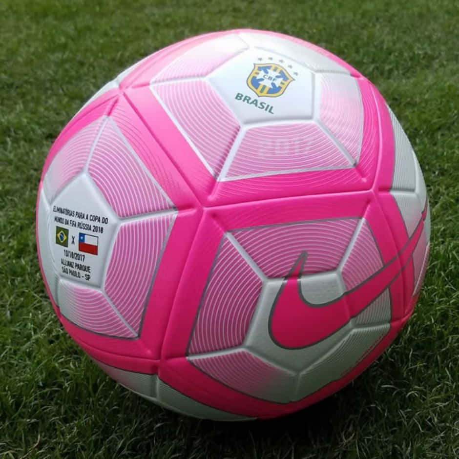 Pink Soccer Ball 桌布 壁紙 — 一個充滿活力的粉紅色和白色Nike足球放在茂盛的綠色草地上，帶有Brazil 2018 World Cup品牌標誌。