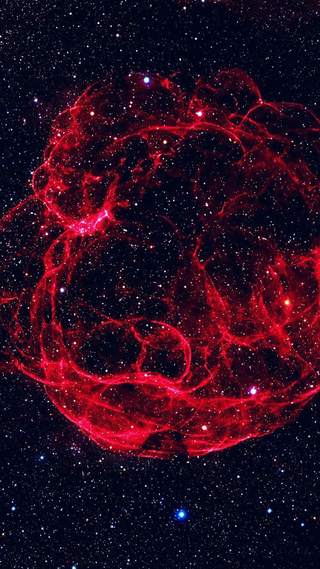 Red Space 桌布 壁紙 — 一個充滿活力的紅色宇宙星雲在深空的星空背景下旋轉。