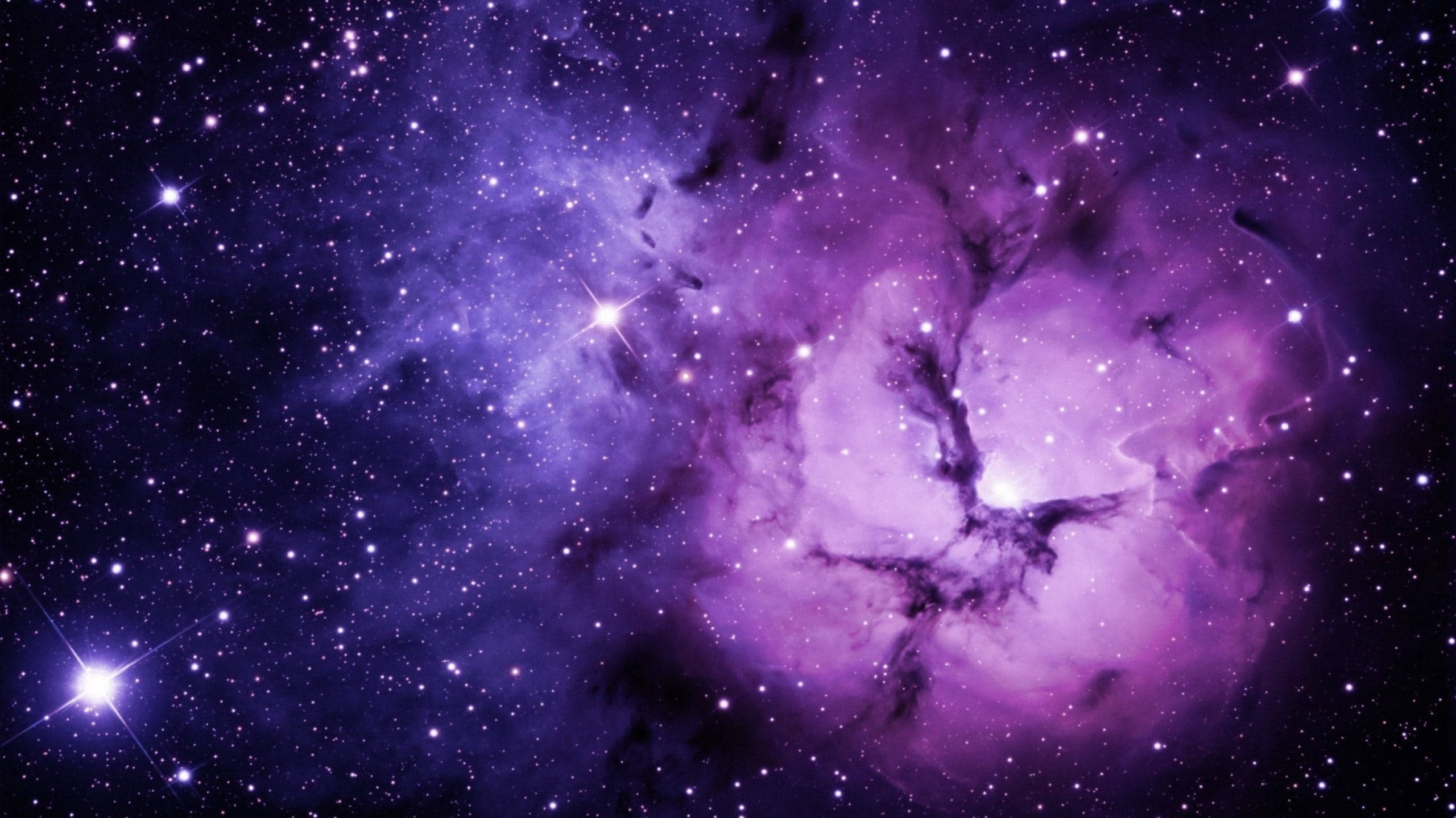 黑紫 桌布 壁紙 — 一個充滿活力的紫色星雲，在深邃的宇宙虛空中，旋轉著發光的氣體和散落的明亮星星。