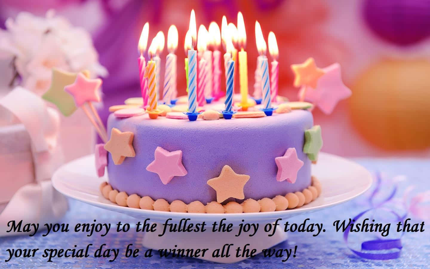 Birthday Wishes 桌布 壁紙 — 一個充滿活力的紫色生日蛋糕，上面點綴著點燃的蠟燭和色彩繽紛的星星裝飾，放在節日的桌子上。