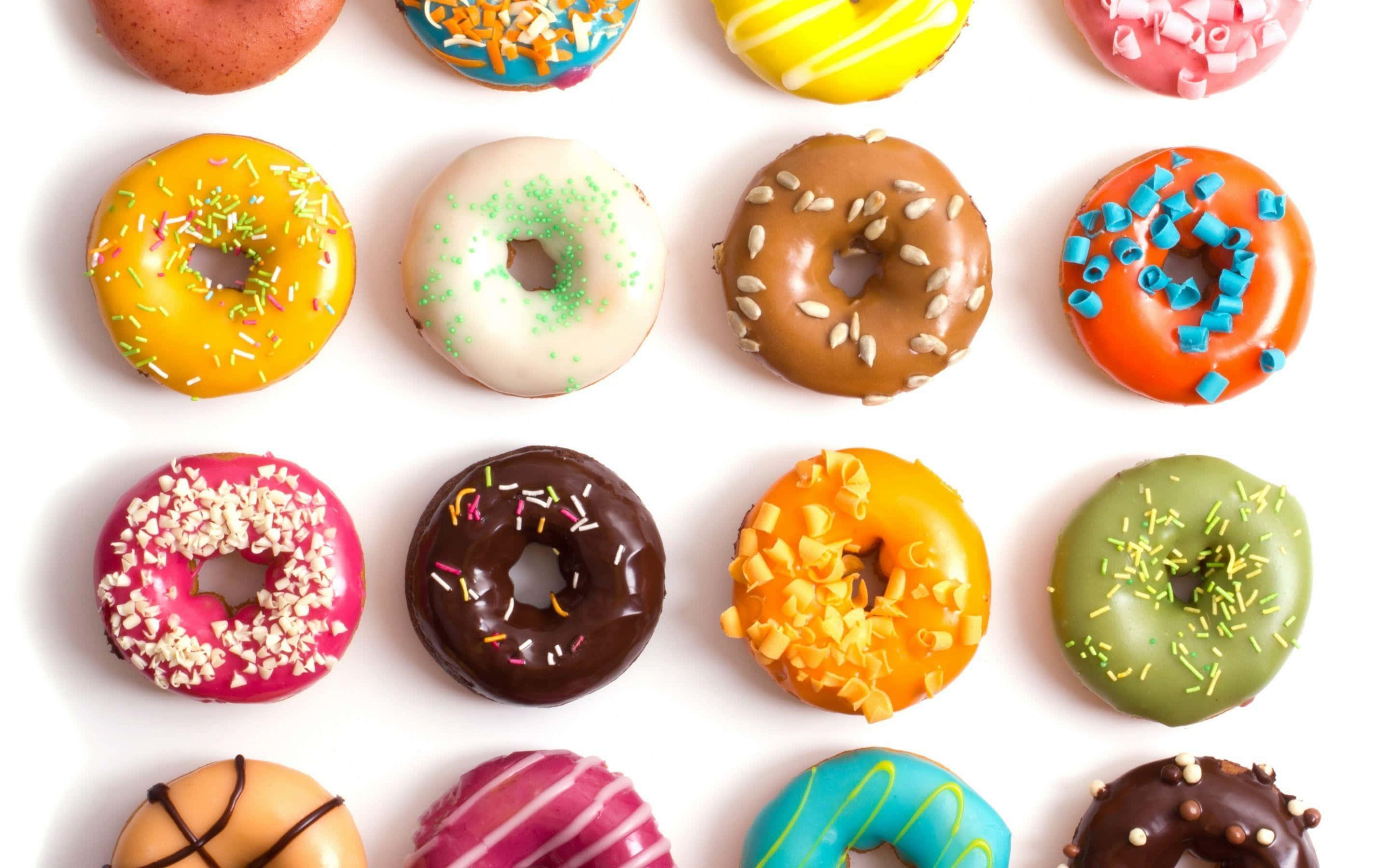 Cute Donut 桌布 壁紙 — 一個充滿活力的網格，展示各種帶有彩色糖霜和配料的冬甩，背景為潔淨的白色。