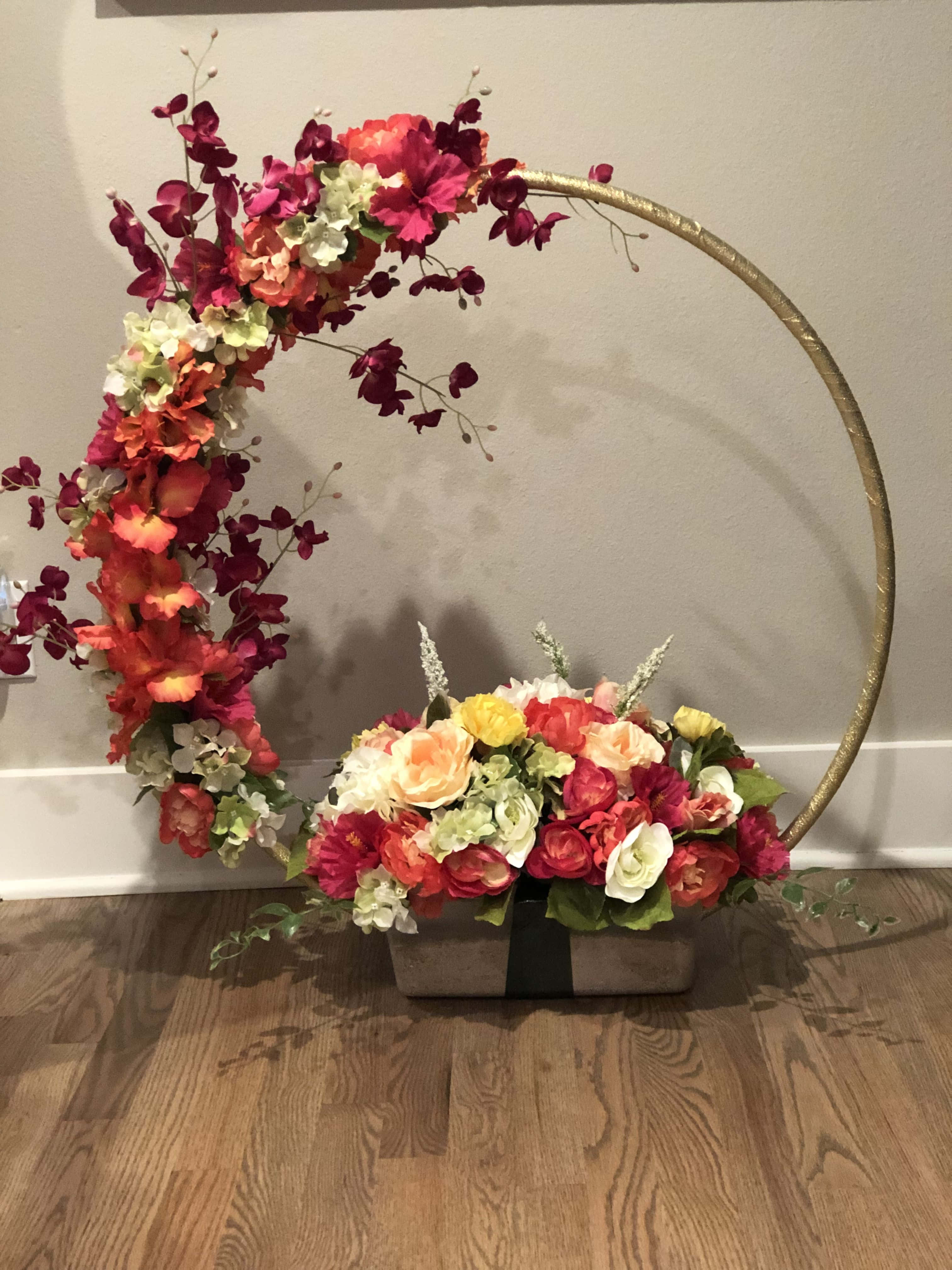 Centerpiece 桌布 壁紙 — 一個充滿活力的花卉佈置從金色圓環傾瀉而下，流入硬木地板上的木箱中。