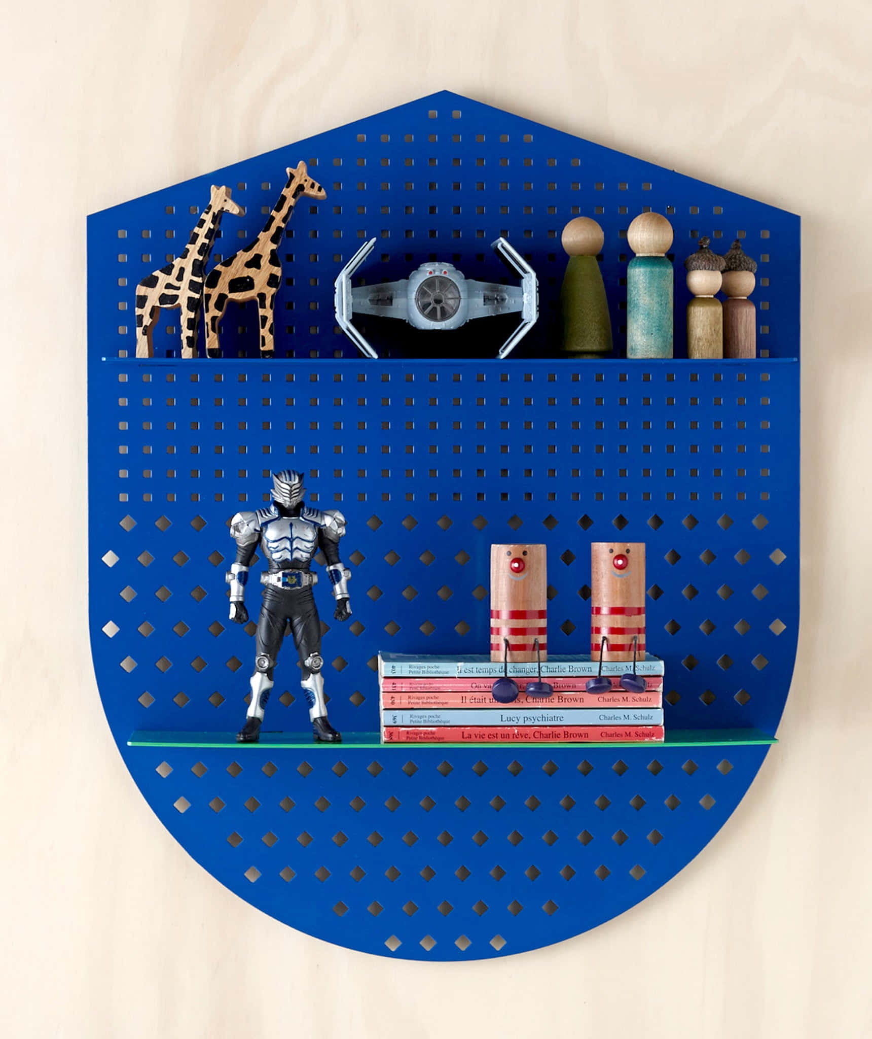 Blue Shield 桌布 壁紙 — 一個充滿活力的藍色六角形 pegboard 牆架，在淺色木質背景上展示了一系列玩具、書籍和木製人偶。