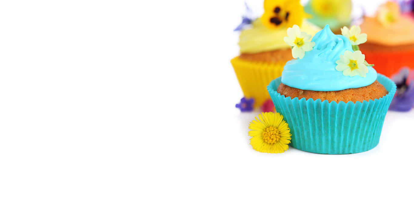 Cute Cupcake 桌布 壁紙 — 一個充滿活力的藍色糖霜杯子蛋糕，點綴著精緻的黃色花朵，旁邊是一朵明亮的黃色雛菊，背景是潔淨的白色。