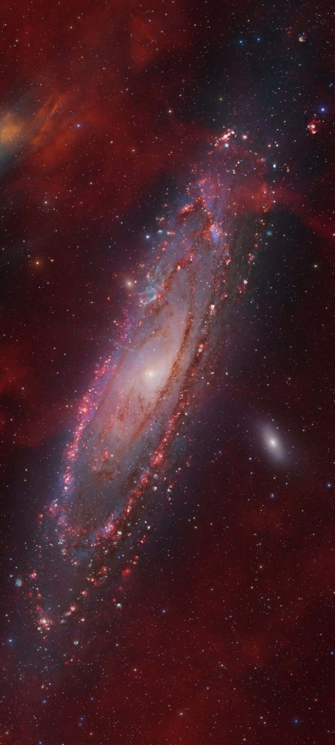 Interstellar Cloud 桌布 壁紙 — 一個充滿活力的螺旋星系，在星空背景下旋轉著紅色、紫色和藍色。