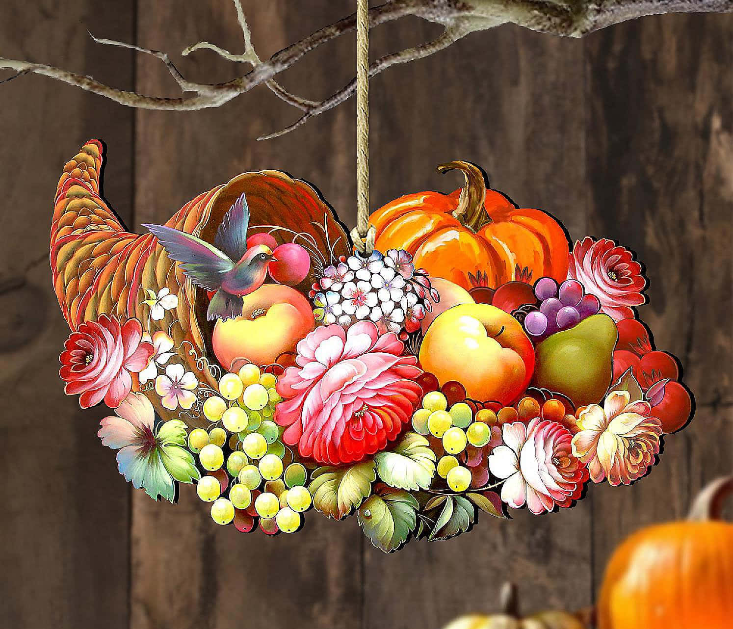 Fall Cornucopia 桌布 壁紙 — 一個充滿活力的豐饒角，裝滿了南瓜、蘋果、葡萄和鮮花，掛在樹枝上，背景是質樸的木質背景。