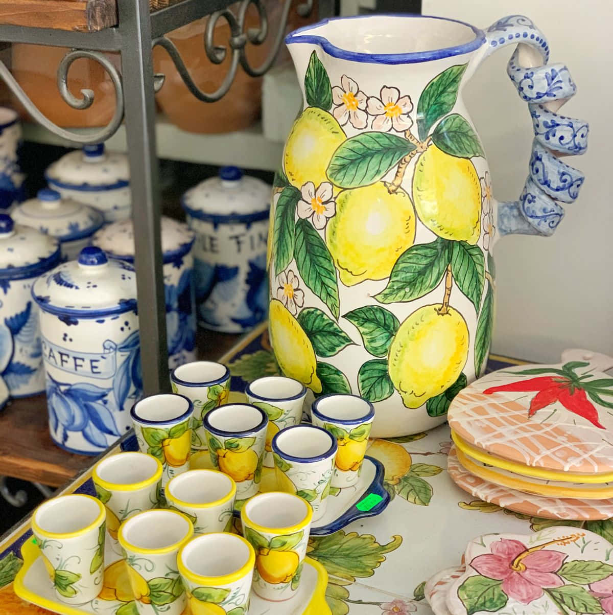 Ceramic 桌布 壁紙 — 一個充滿活力的陶瓷壺和杯子，飾有檸檬和花朵，放在相配的桌布上，周圍環繞著藍白陶瓷。
