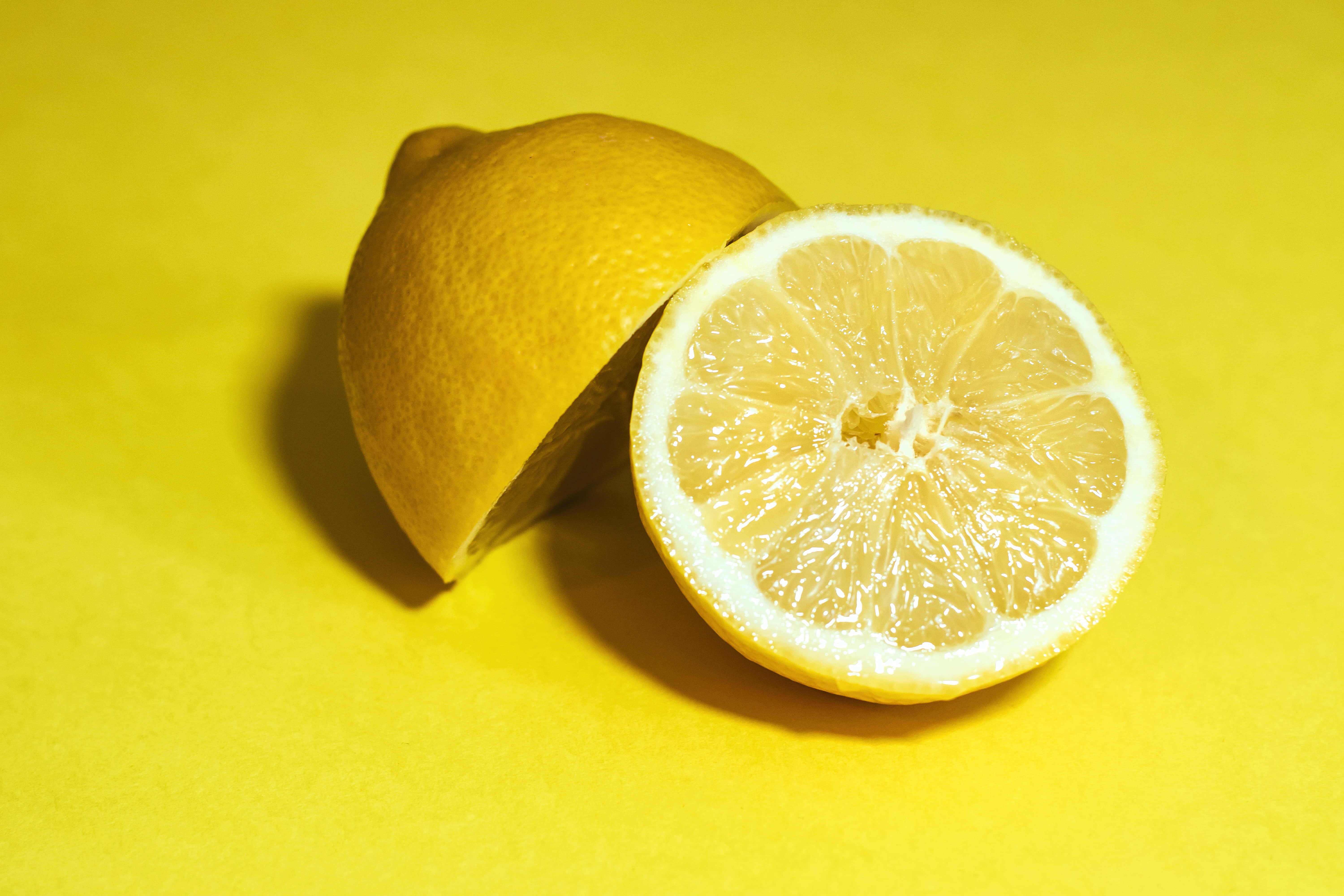 Summer Fruits 桌布 壁紙 — 一個充滿活力的黃色檸檬切成兩半，在純黃色背景上顯露出多汁的果瓣。