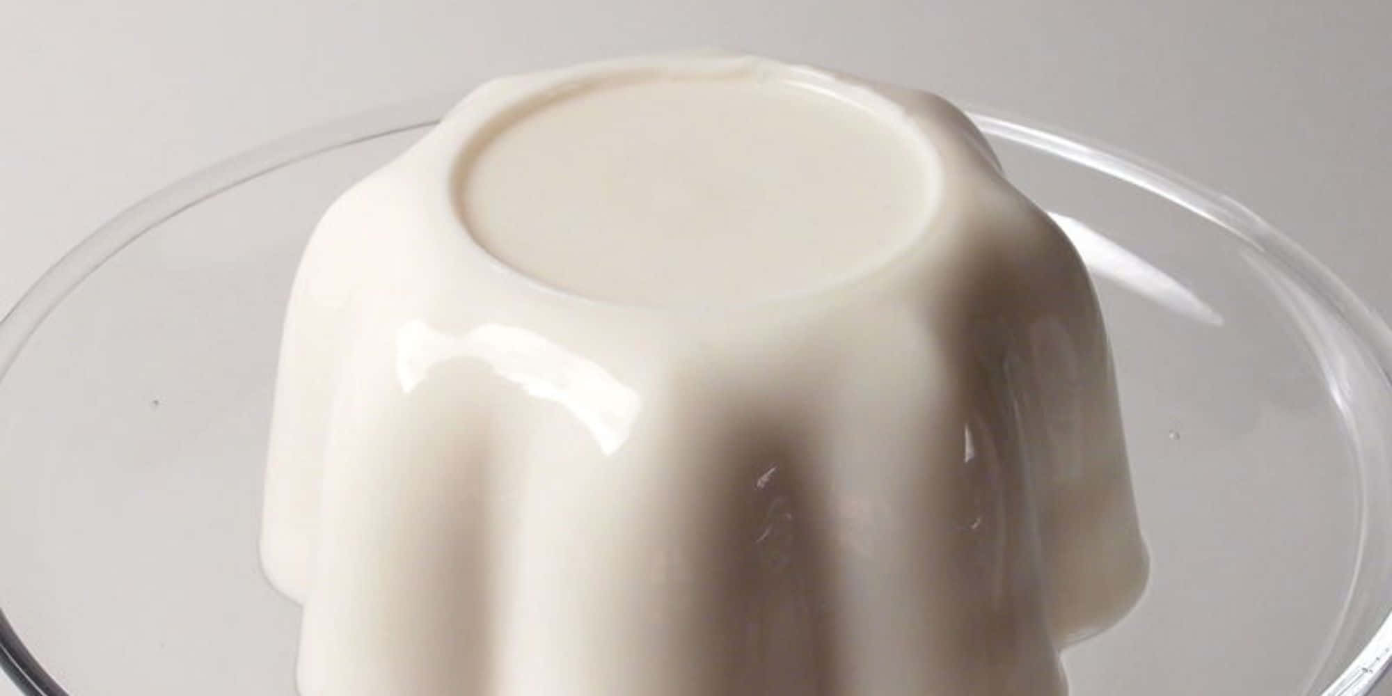 Blancmange 桌布 壁紙 — 一個光滑的奶油白色布丁，放在帶有凹槽的玻璃碟中，光線柔和，陰影輕柔。