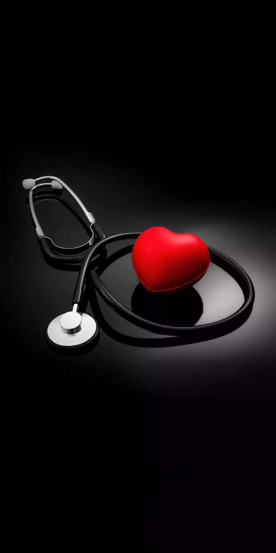 Health And Beauty 桌布 壁紙 — 一個光滑的紅色心形物體放在黑色聽診器旁邊，置於反射黑色表面上，在戲劇性燈光下。