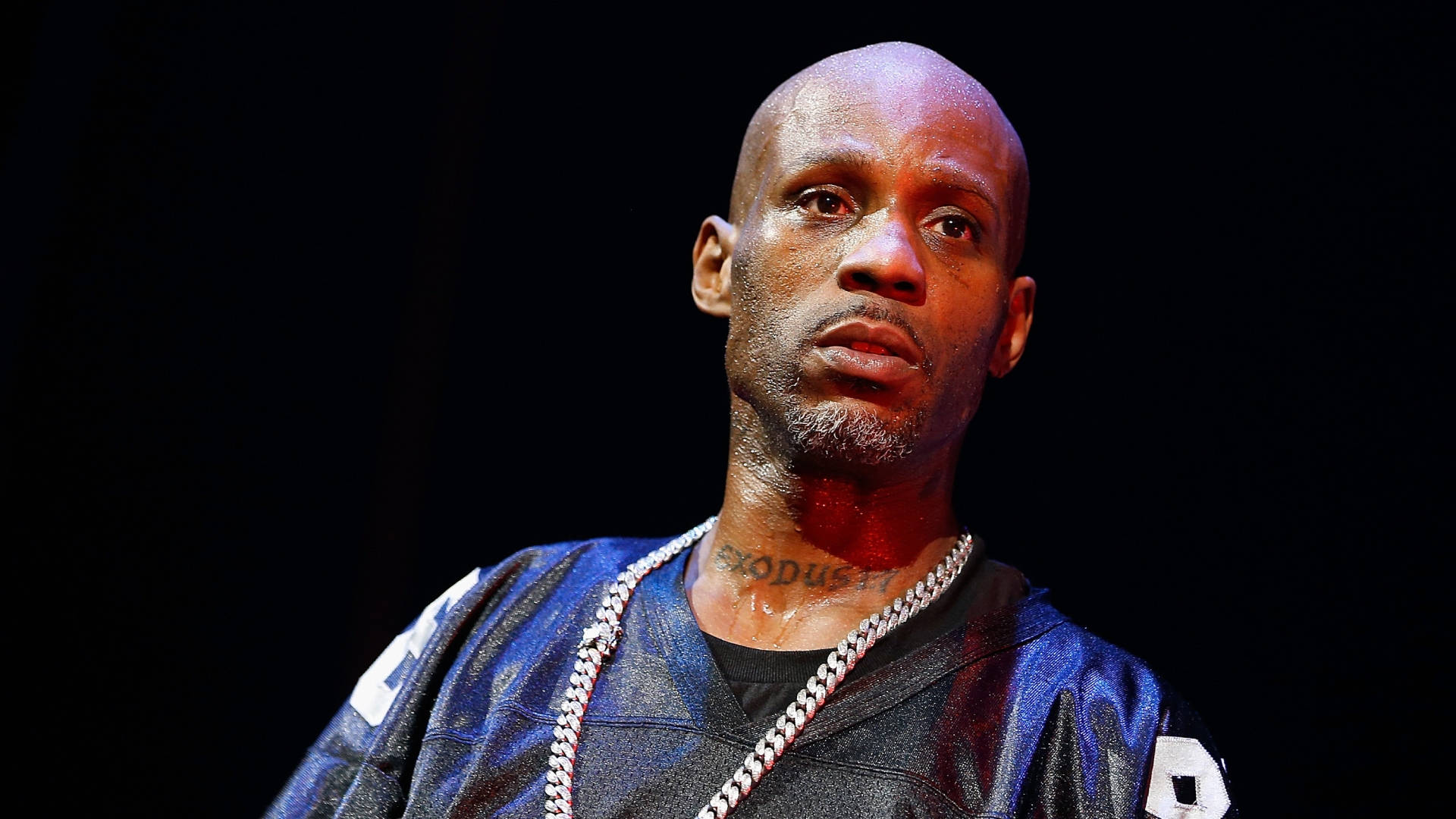 Earl Simmons DMX 壁紙 — 一個光頭、留山羊鬍、戴粗鏈條項鍊的男人，在黑色背景下強烈凝視。