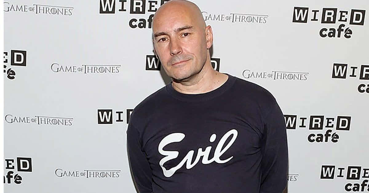 Grant Morrison 桌布 壁紙 — 一個光頭男人穿著印有白色 'Evil' 字樣的黑色T恤，站在 'Game of Thrones' 和 'Wired cafe' 品牌背景前。