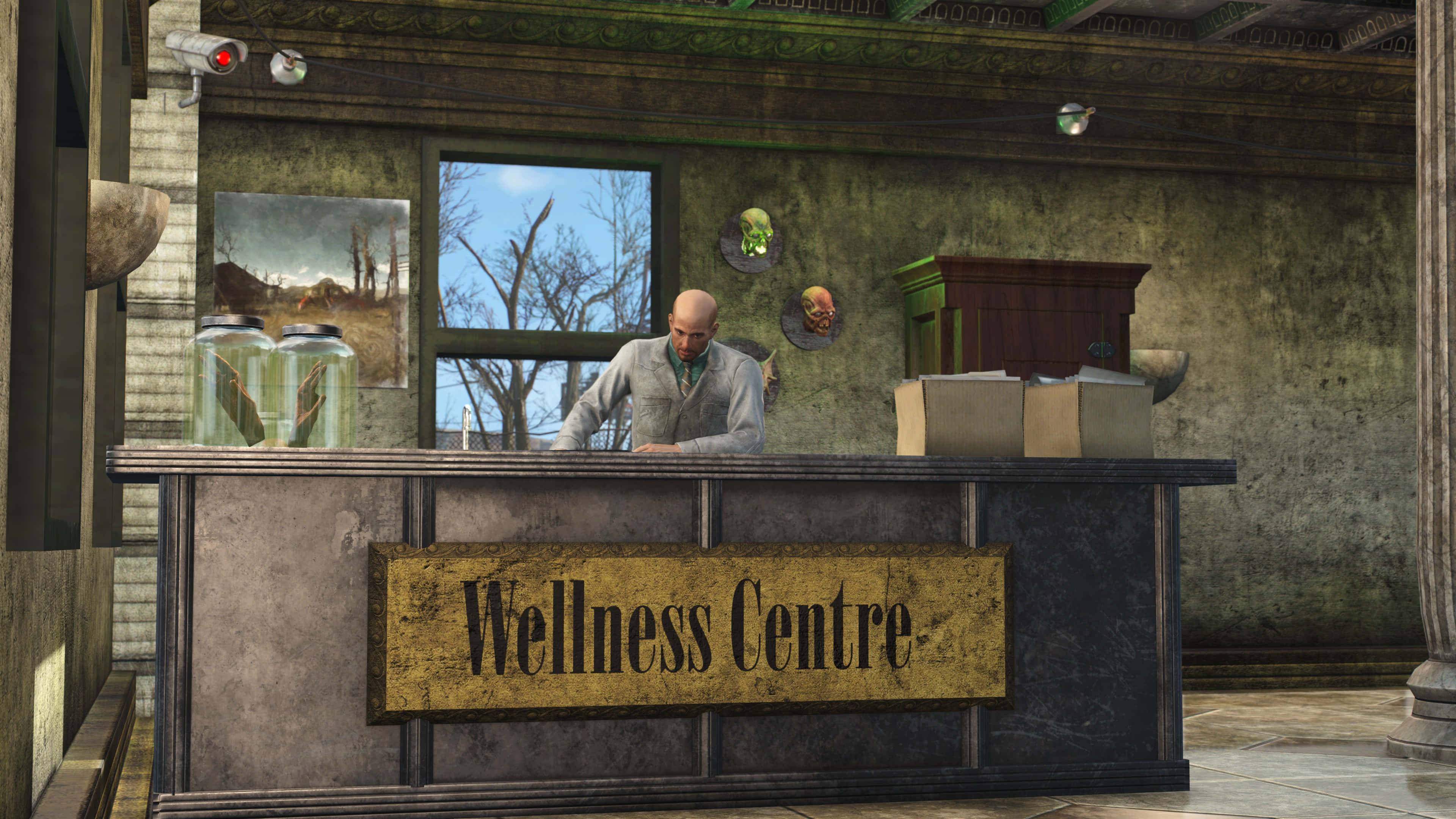 Fallout 4 The Capital Wasteland 桌布 壁紙 — 一個光頭男人穿著灰色外套，站在一個寫著「Wellness Centre」的破舊櫃檯後面，身處一棟骯髒廢棄的建築物內，窗外可見光禿禿的樹木。