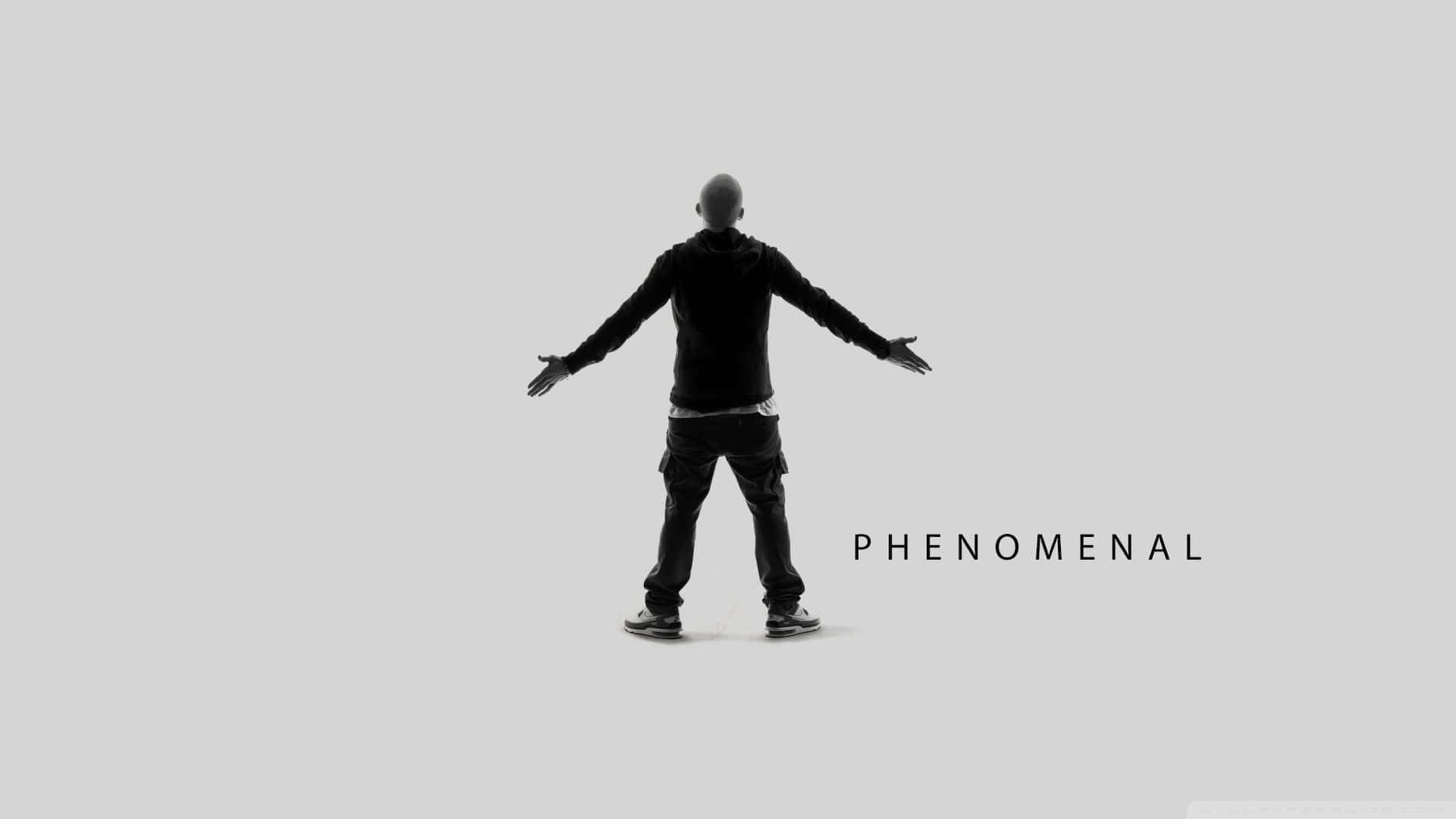 Eminem 桌布 壁紙 — 一個光頭男子穿著黑色連帽衫，在純灰色背景前張開雙臂站立，下方有phenomenal這個詞。