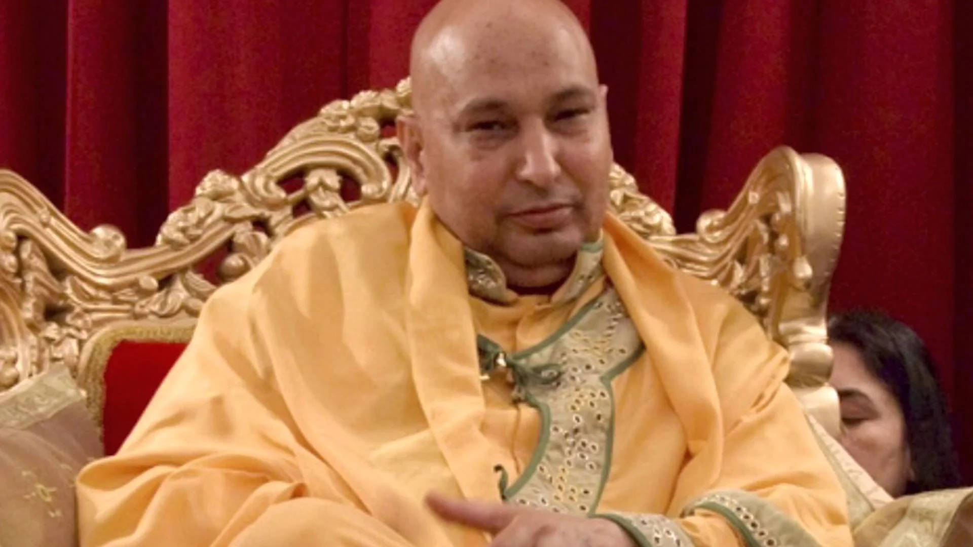 Master 桌布 壁紙 — 一個光頭男子身穿金色長袍，威嚴地坐在華麗的寶座上，背景是深紅色窗簾。